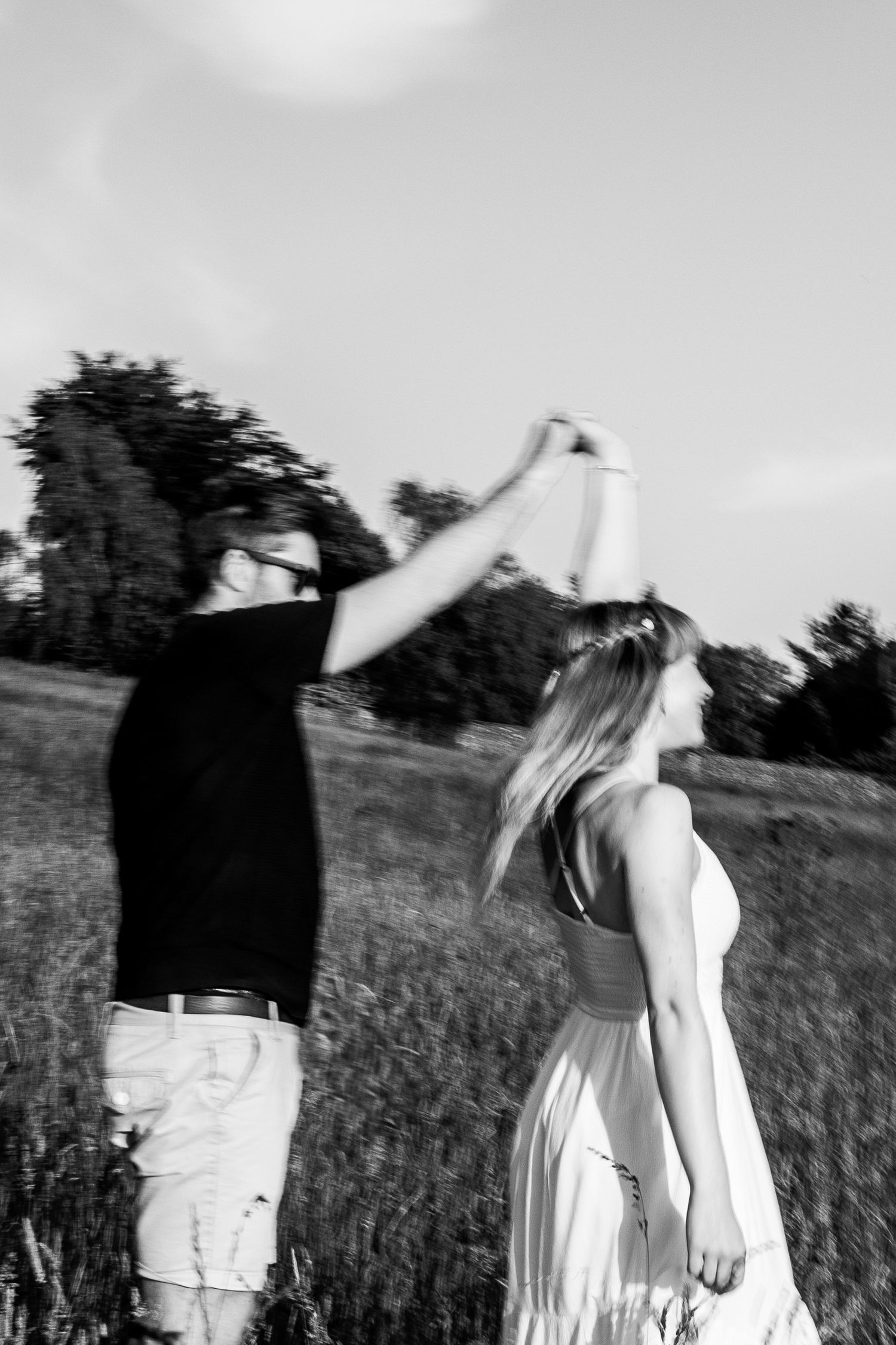 Black and white photos of people in white dresses spinning and dancing in a meadow.