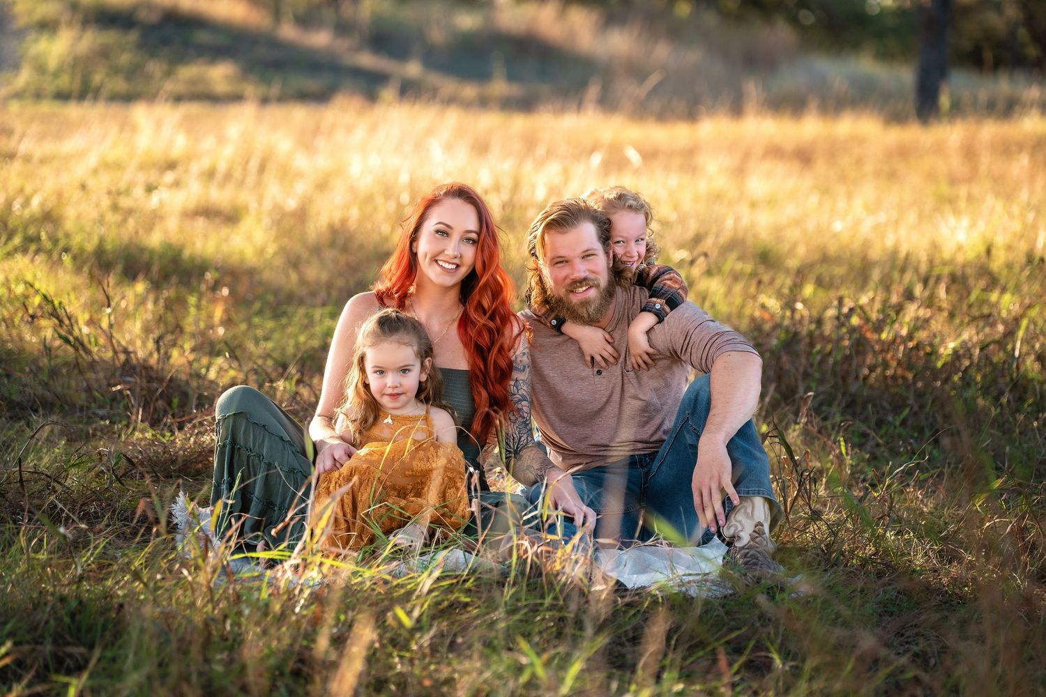 Family and golden retriever dog relaxing together in a sun-drenched meadow at sunset.