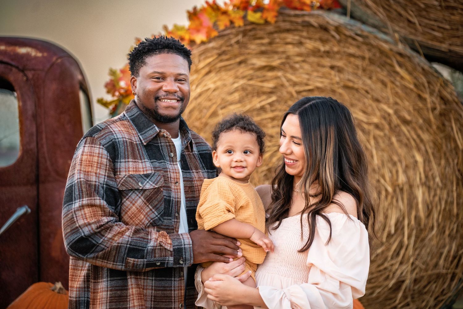 A family bonds together and smiles during a rustic autumn photoshoot session at the farm.
