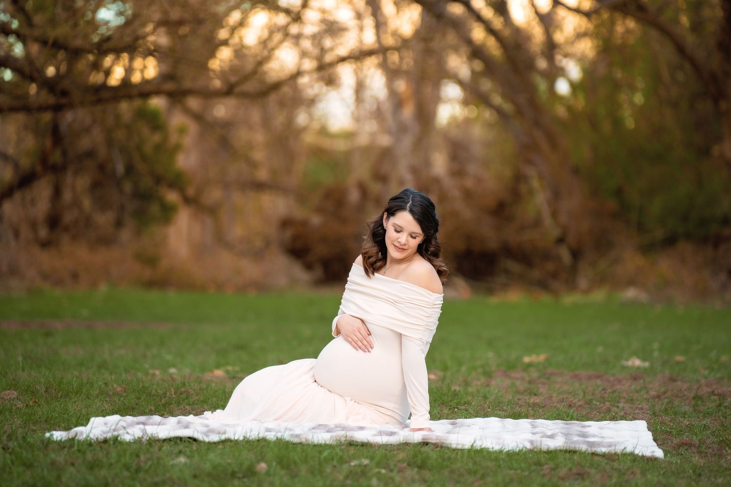 An outdoor maternity photo session with elegant poses on a white blanket in Wimberley, TX