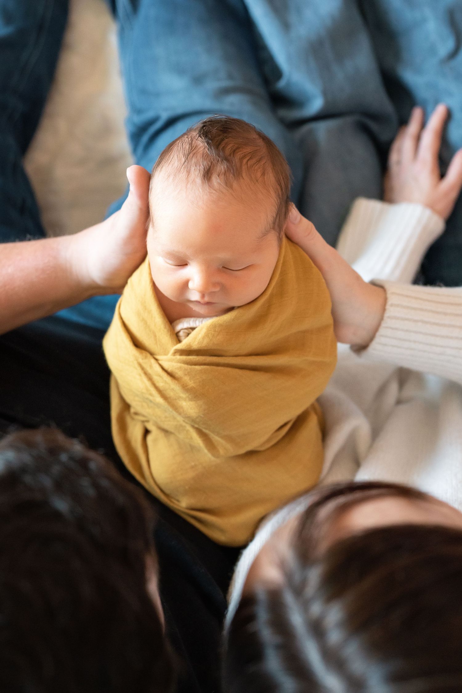 Baby wearing yellow outfit being held during intimate indoor moment.