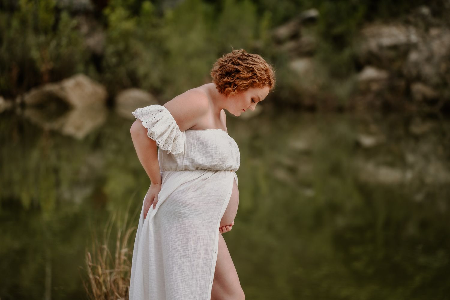 Soft white dress detail photographed against blurred natural green background.
