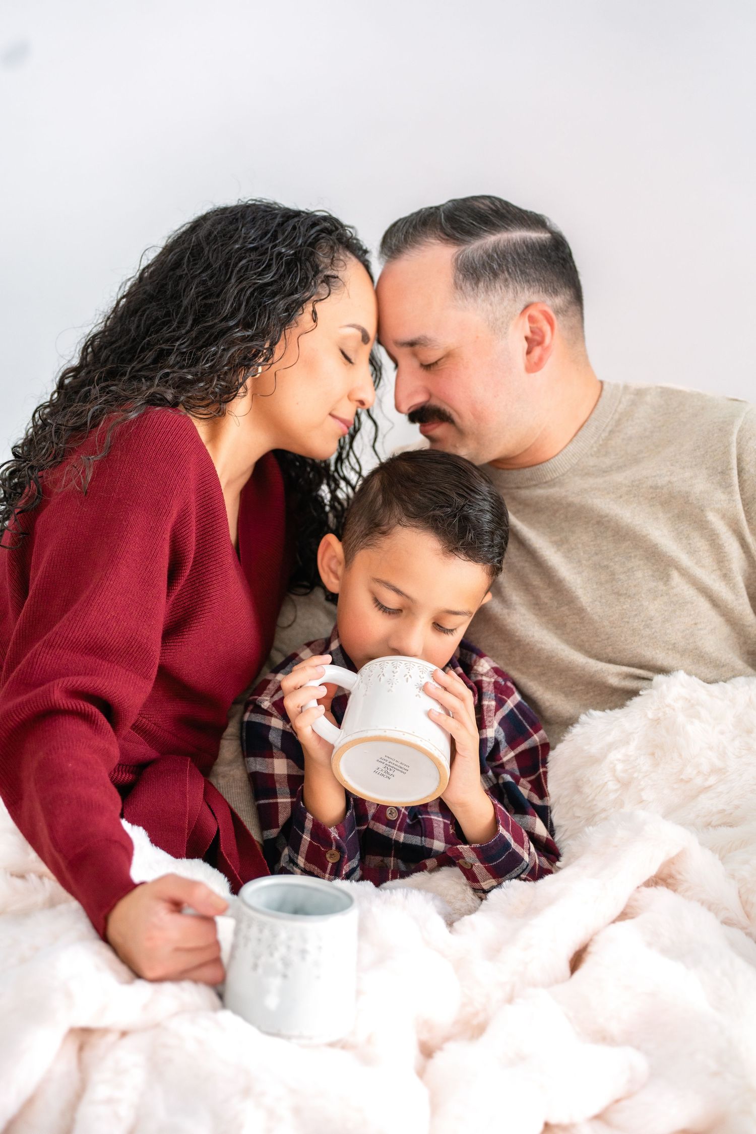 Family sharing tender moments together while resting on soft blankets during intimate photo session.