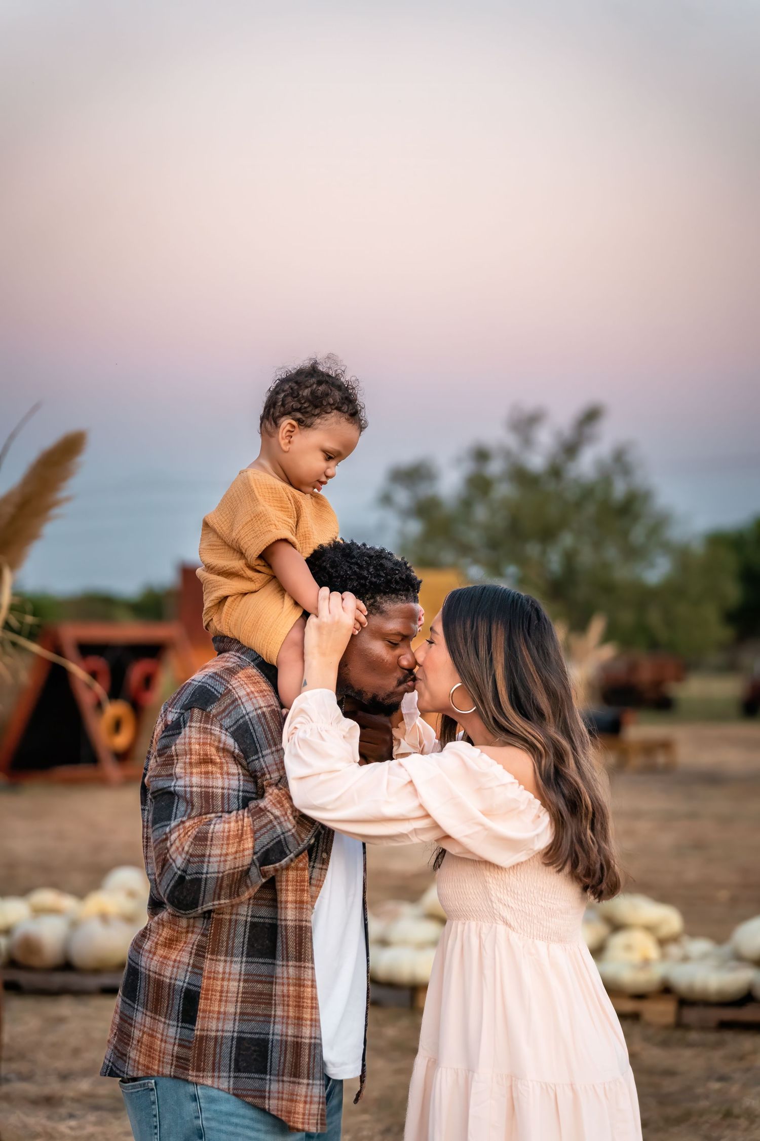 A family enjoys an autumn moment together in a pumpkin patch during sunset.