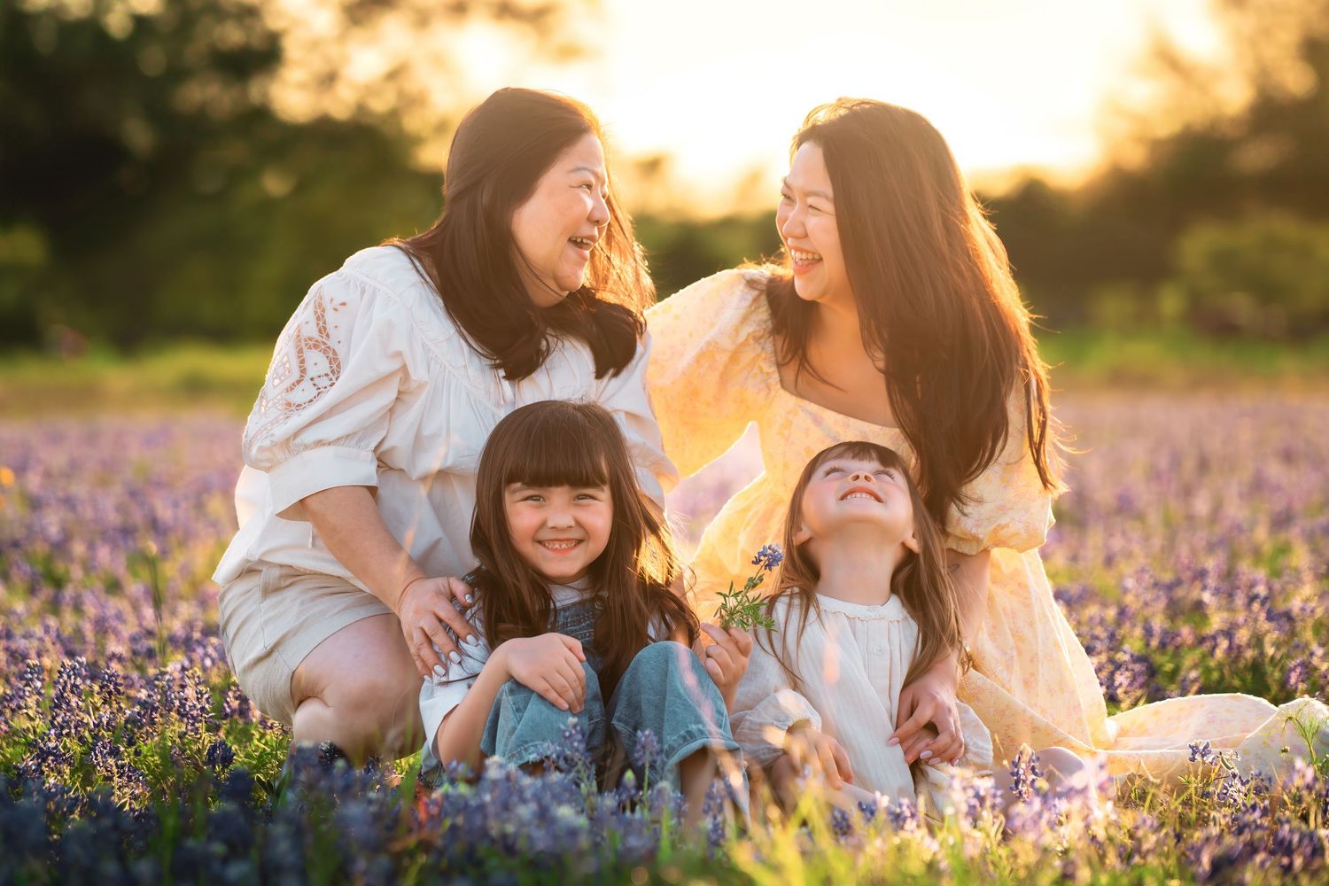 Family enjoying a sunset moment together in a blooming purple wildflower field during golden hour.