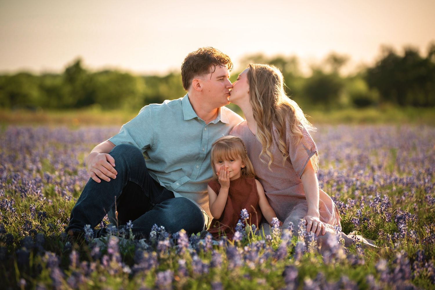 A romantic couple shares tender moments in a blooming purple wildflower field at sunset.