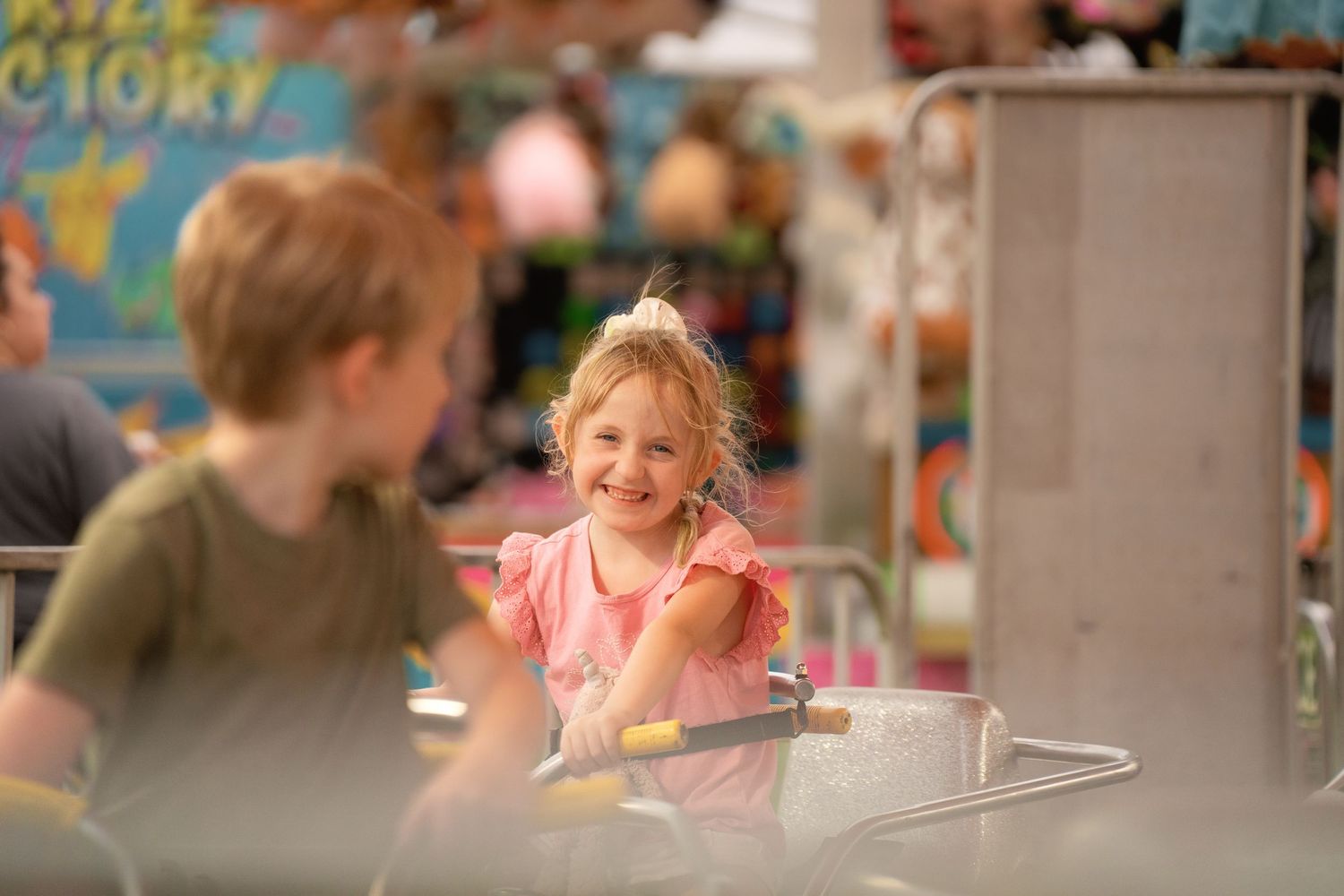 Two young children laughing and enjoying a carnival ride at an amusement fair.