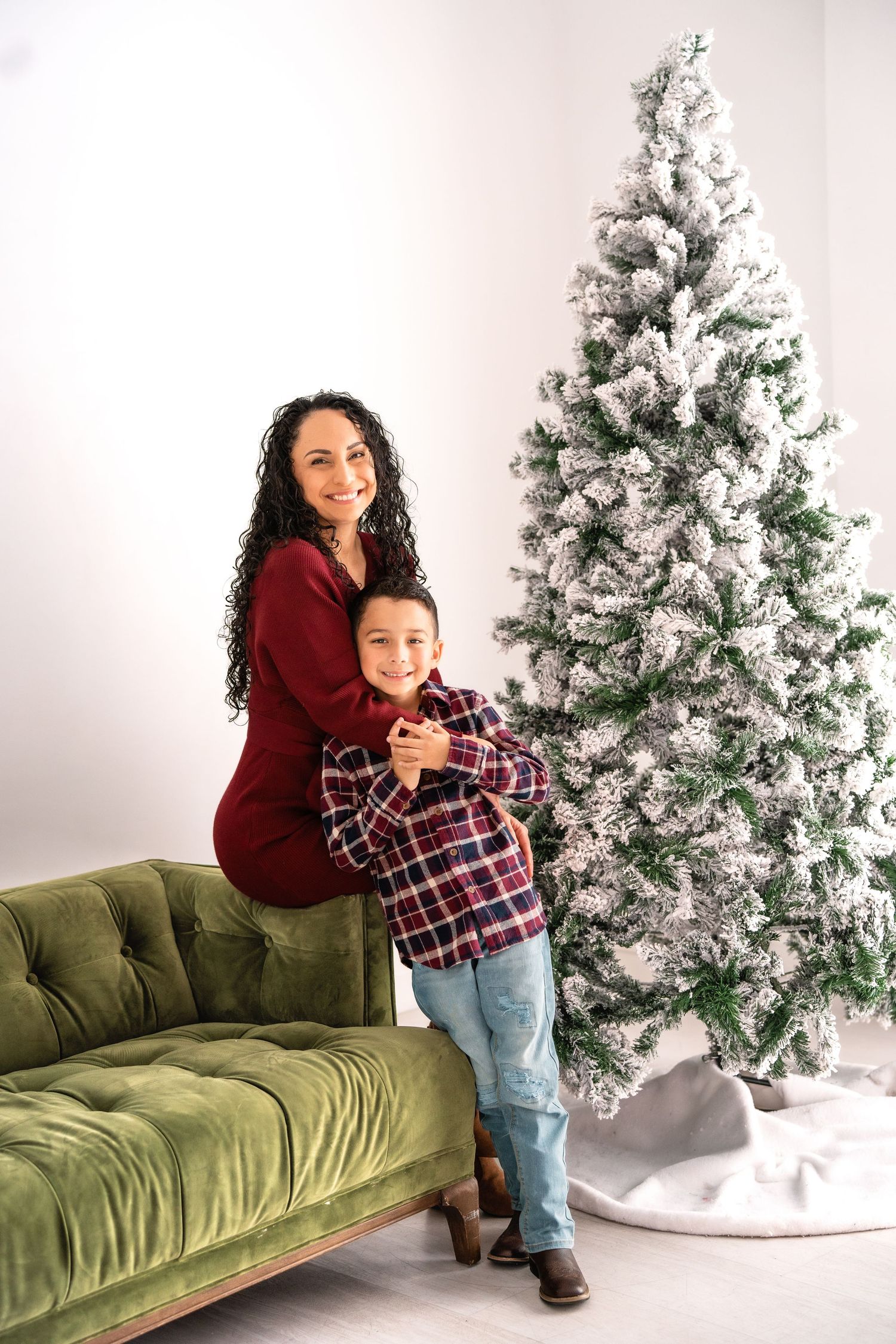 A set of holiday photos with a green velvet couch and flocked Christmas tree in a white studio setting.