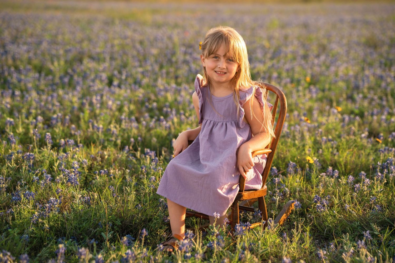 A child in a lavender dress explores a vibrant field of wildflowers during golden hour.