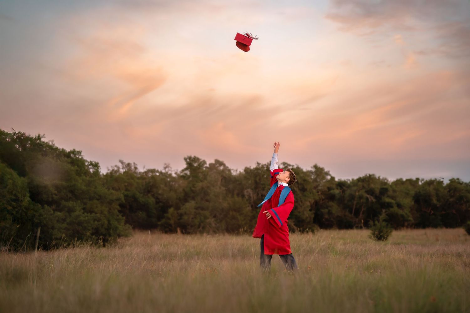 Red heart-shaped balloons floating against sunset sky in open field.