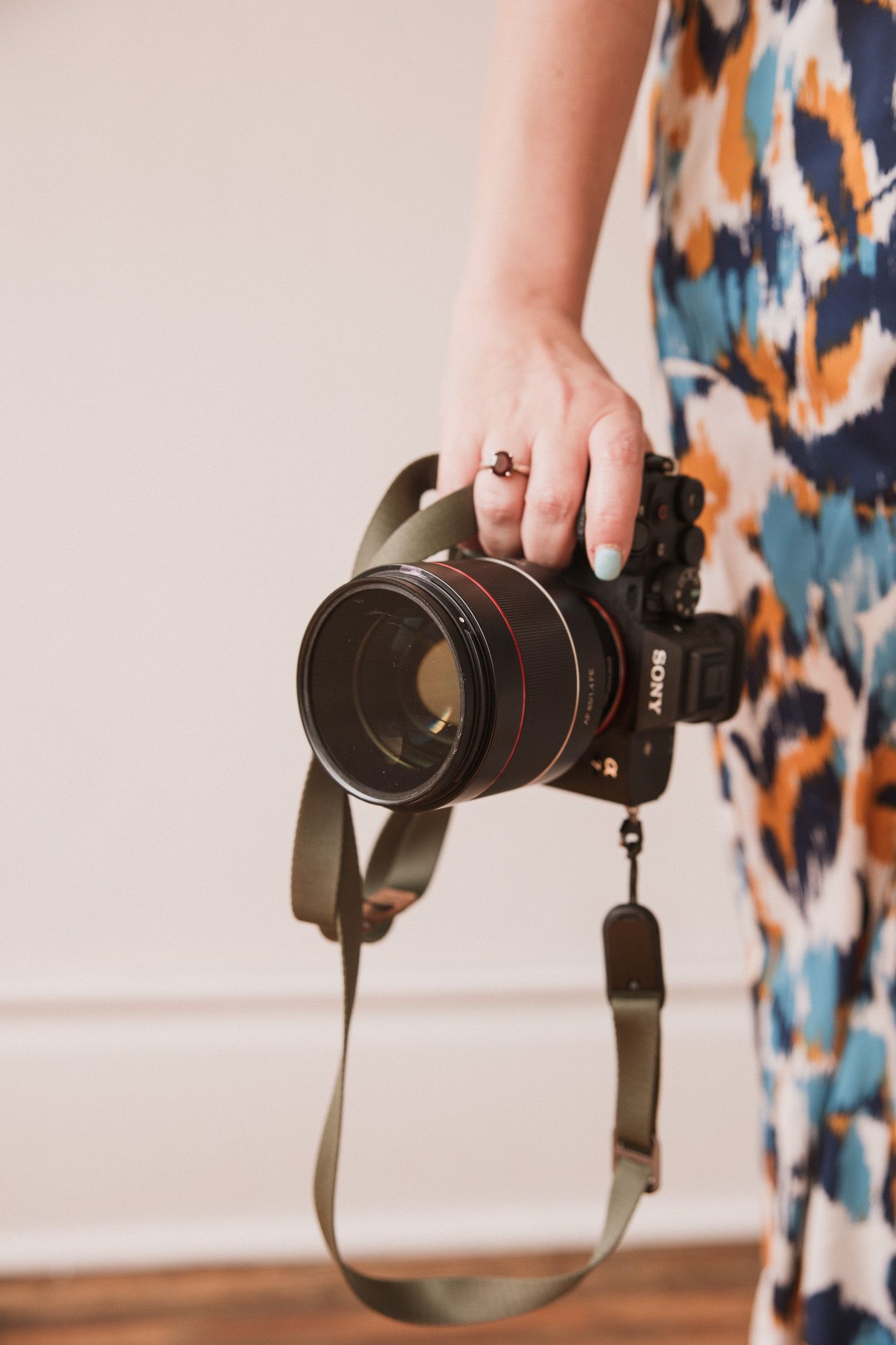 A professional camera with telephoto lens shown in a series of rotating angles against a soft background with abstract art.