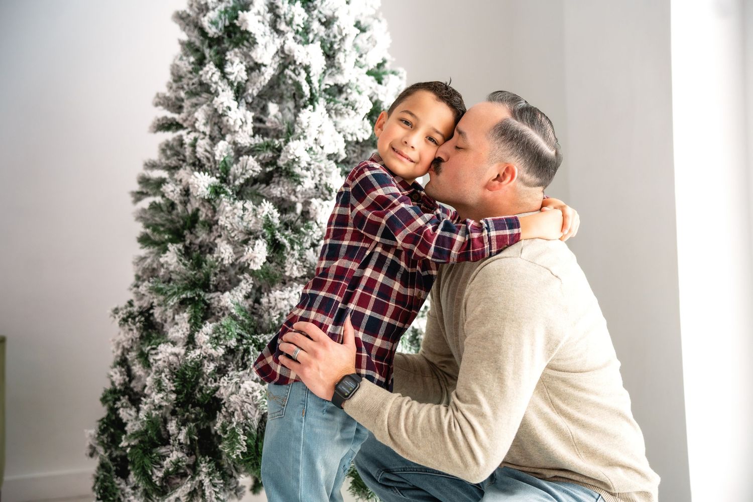 Family sharing a joyful moment on the sofa with festive holiday decorations visible behind them.