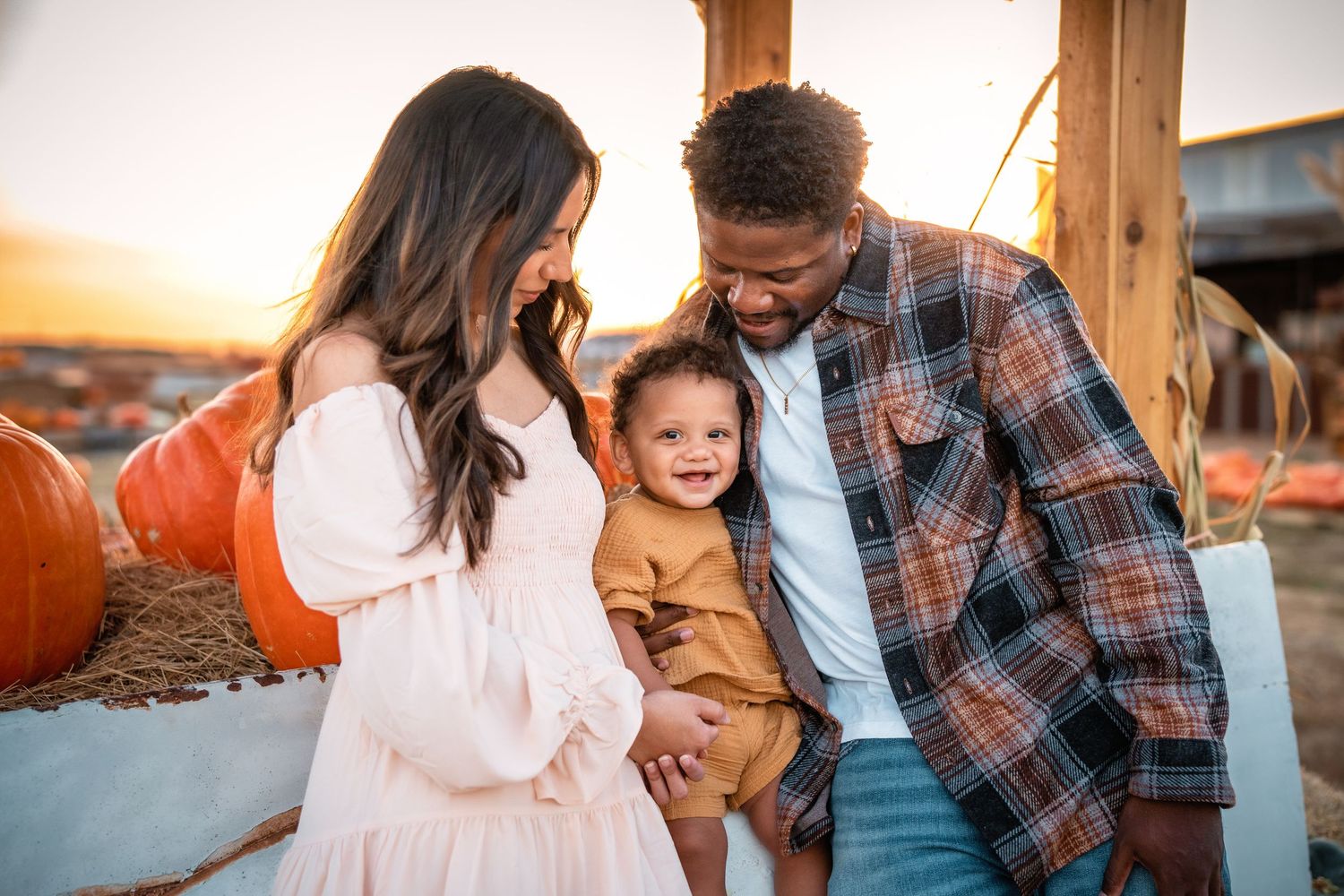 Family in casual attire enjoying a tender moment together during golden hour at sunset.