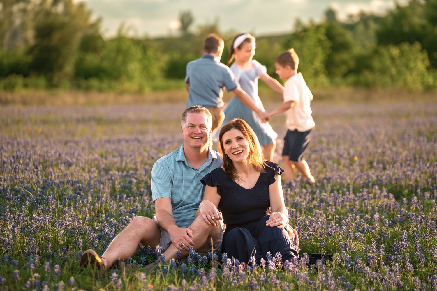 People sitting together in a beautiful field of blooming purple wildflowers during a sunny summer day.