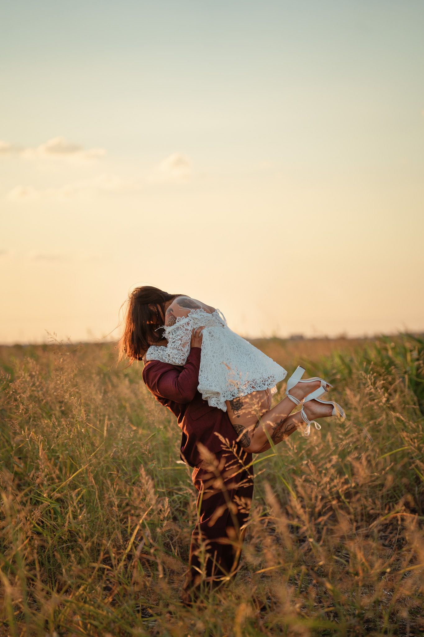 A figure in a flowing white dress dances gracefully through a golden wheat field at sunset.