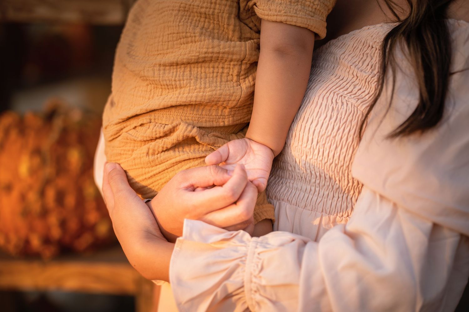 A close-up of hands holding hot coffee in a brown cup during sunset.