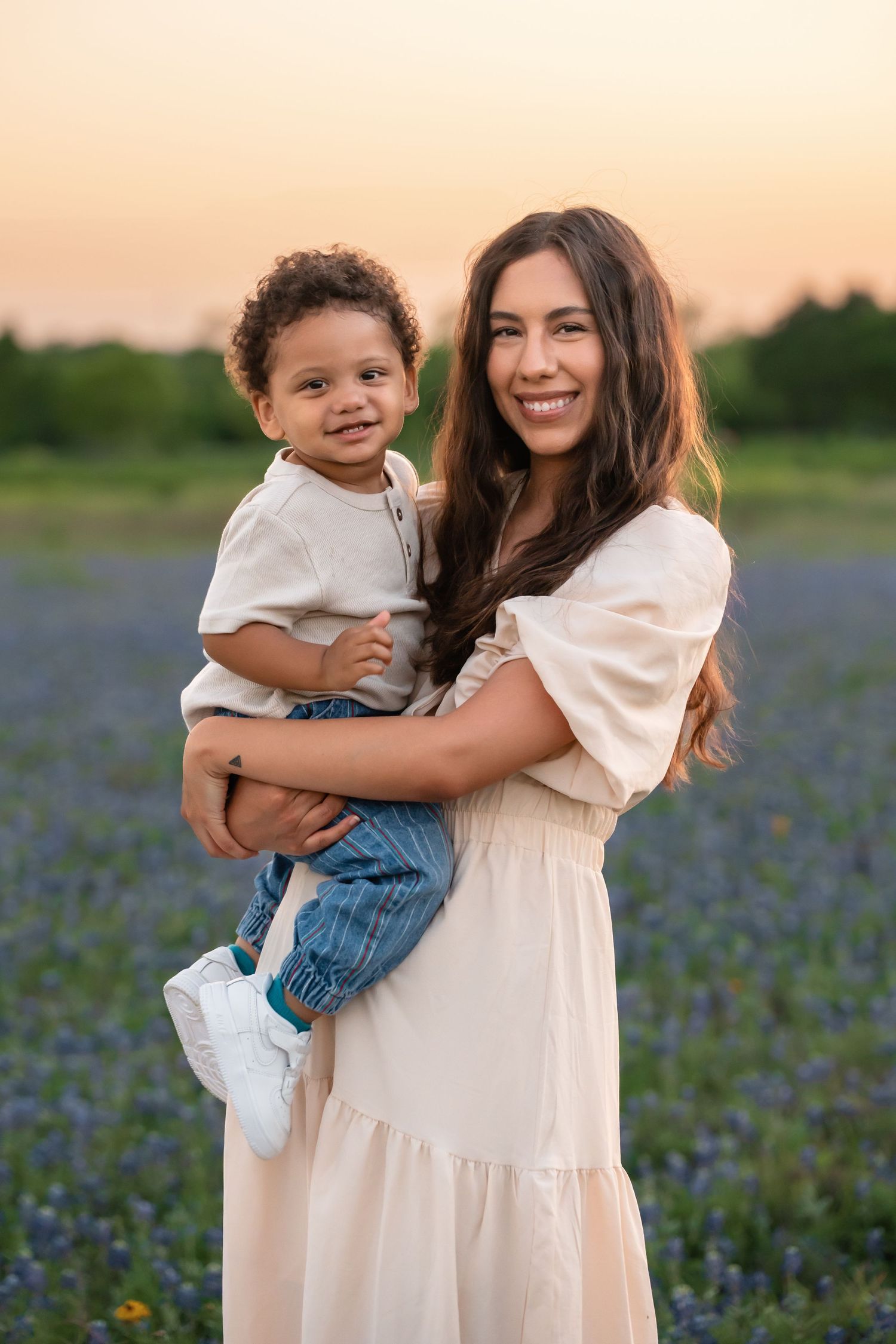 A pair in a field of blooming bluebonnets share a tender moment during golden hour.