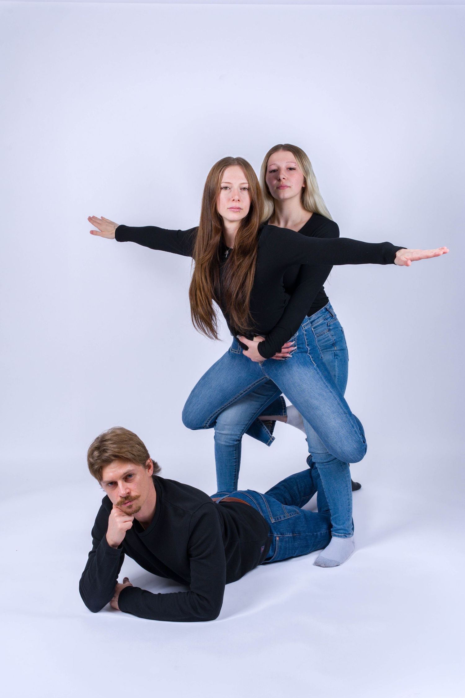 Three artistic poses show people in black tops and blue jeans creating dynamic shapes against a white studio backdrop.