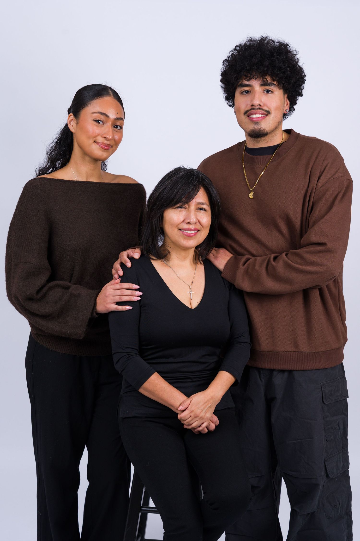 A couple wearing matching black and brown outfits poses together in a series of casual studio photos.