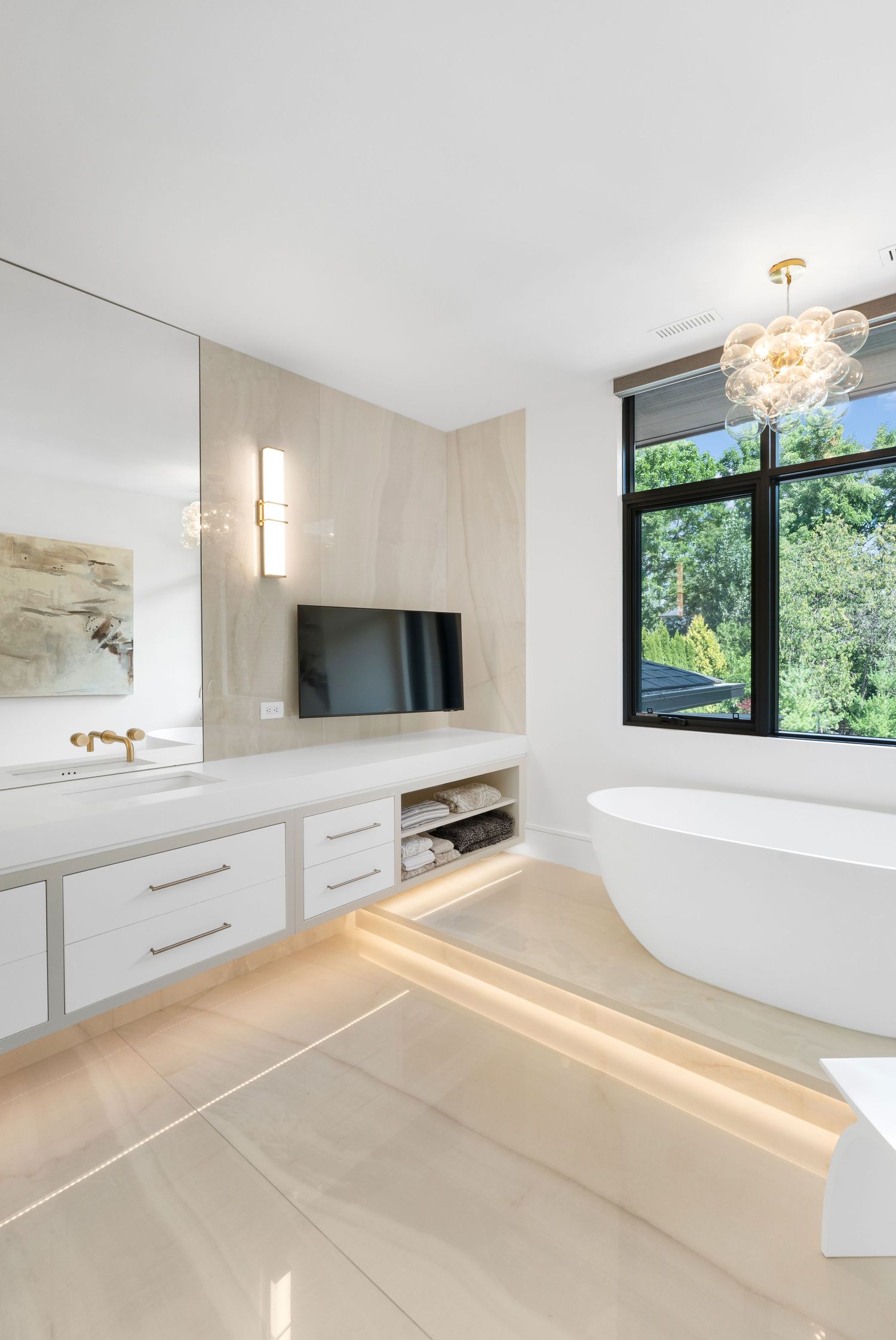 Luxurious master bathroom with freestanding tub, white cabinetry, and large windows bringing in natural light.