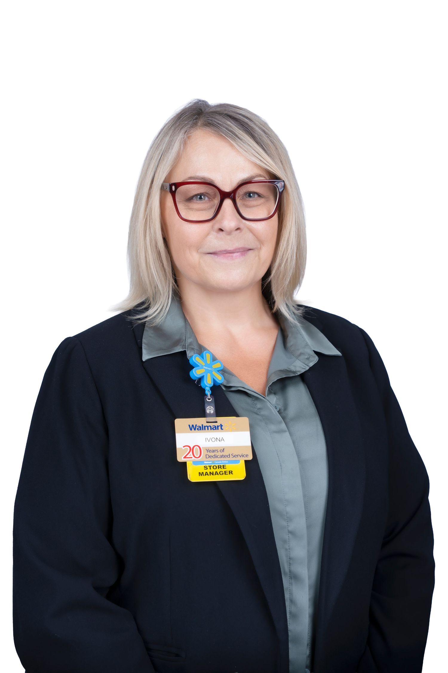 Professional headshot of a staff member wearing glasses, a black blazer and name badge against white background.