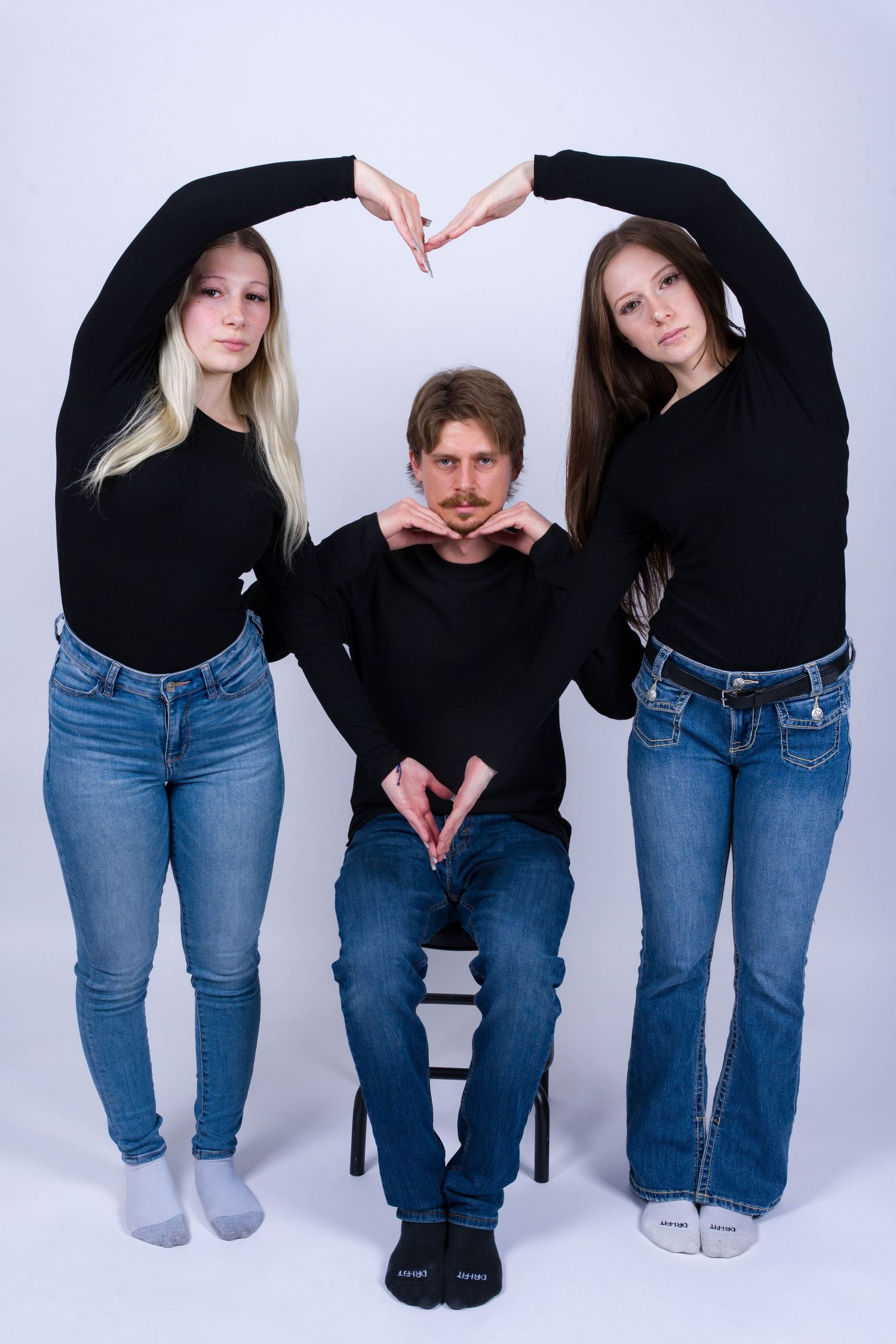 Series of cropped photos showing people wearing black tops and blue jeans in various casual poses against white background.
