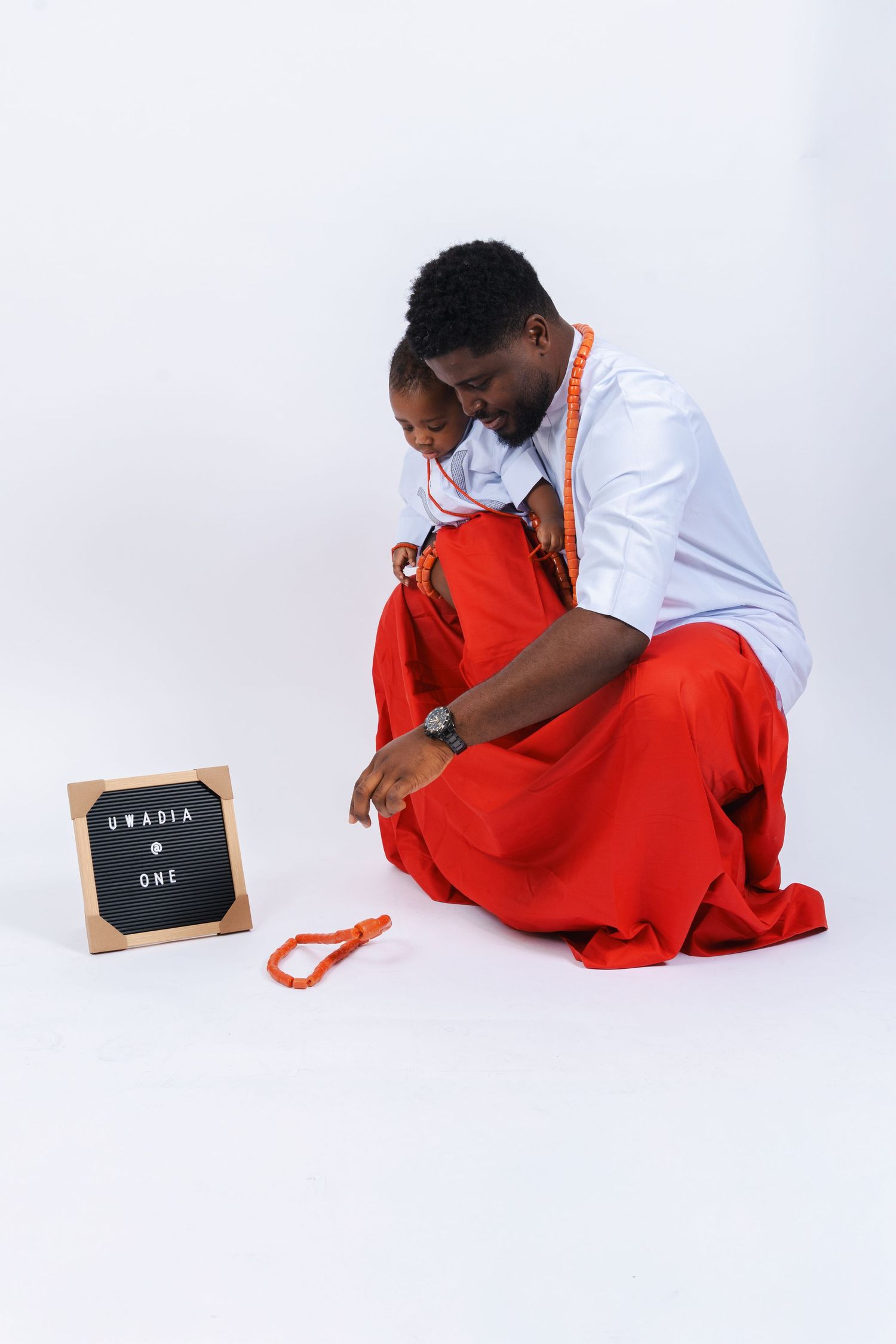 Person in white shirt and red pants writes on small chalkboard while sitting on floor in sequence of three poses.