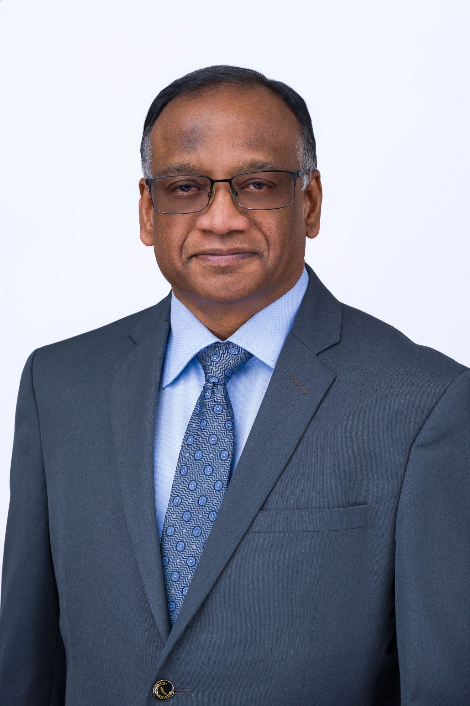 Professional headshot series of person in navy suit and blue patterned tie against light background.