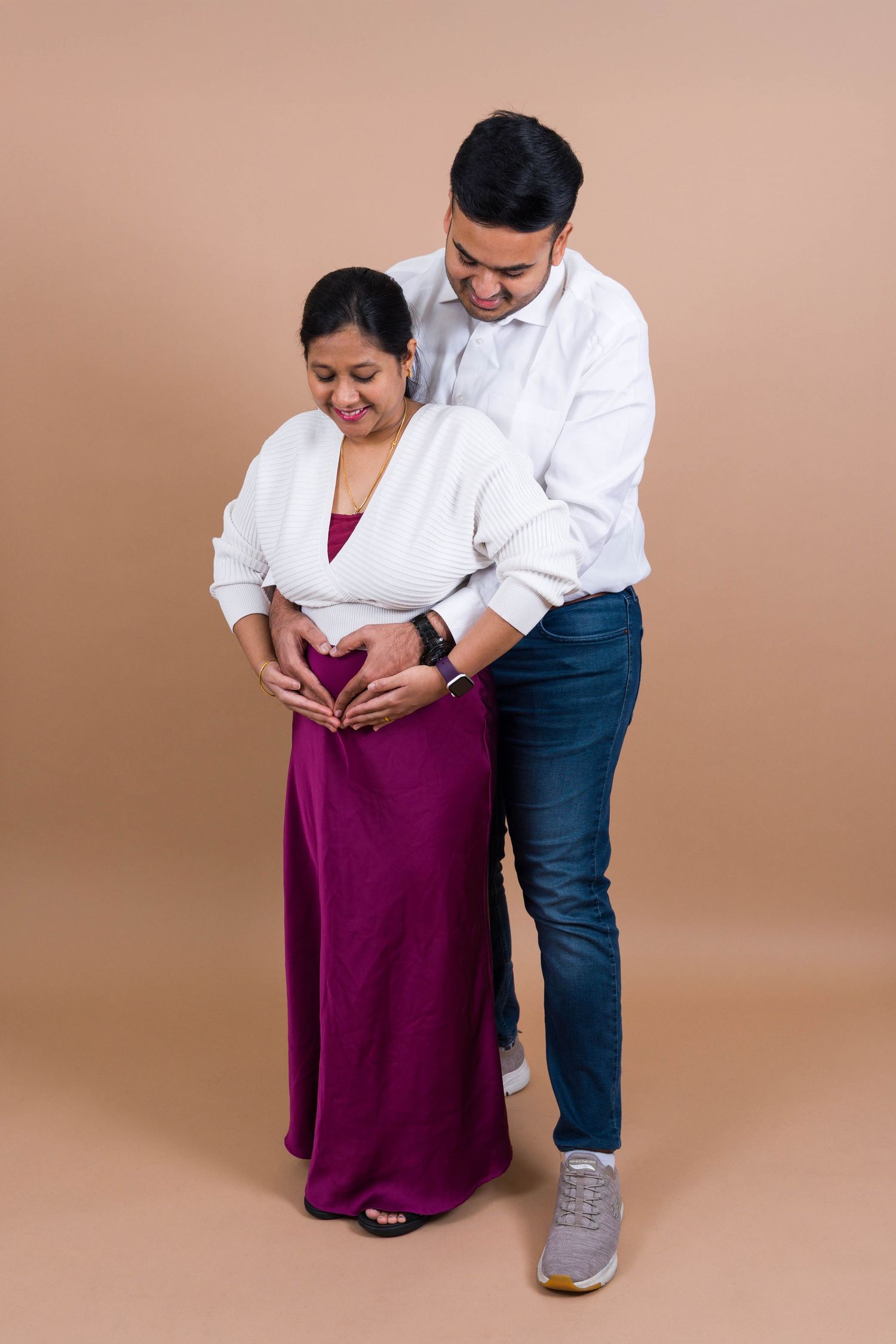 Four sequential photos showing a couple in a tender moment against a beige background, wearing white and purple outfits.