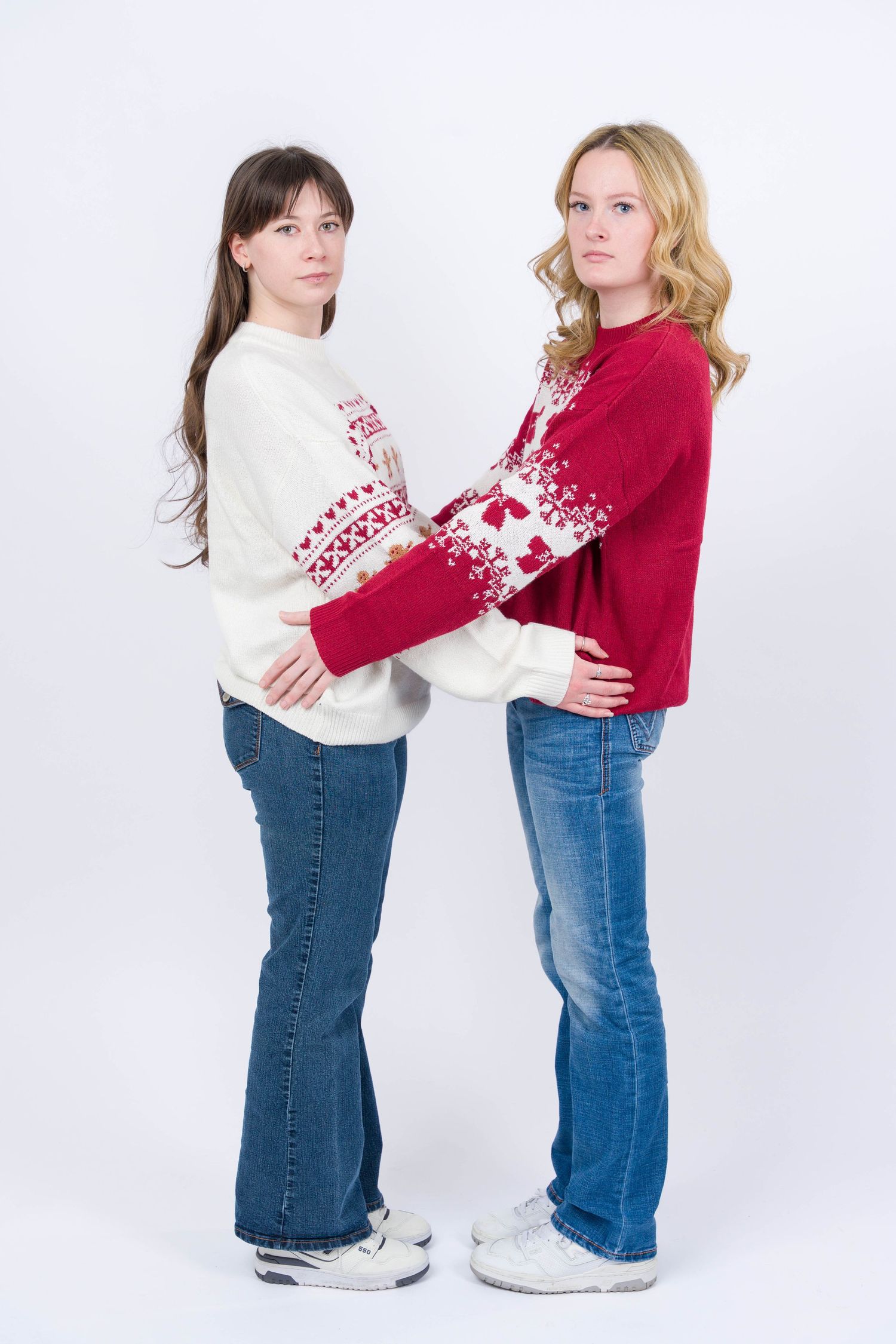 Two children in jeans and sweaters playfully push each other in a sequence of photos against a white backdrop.