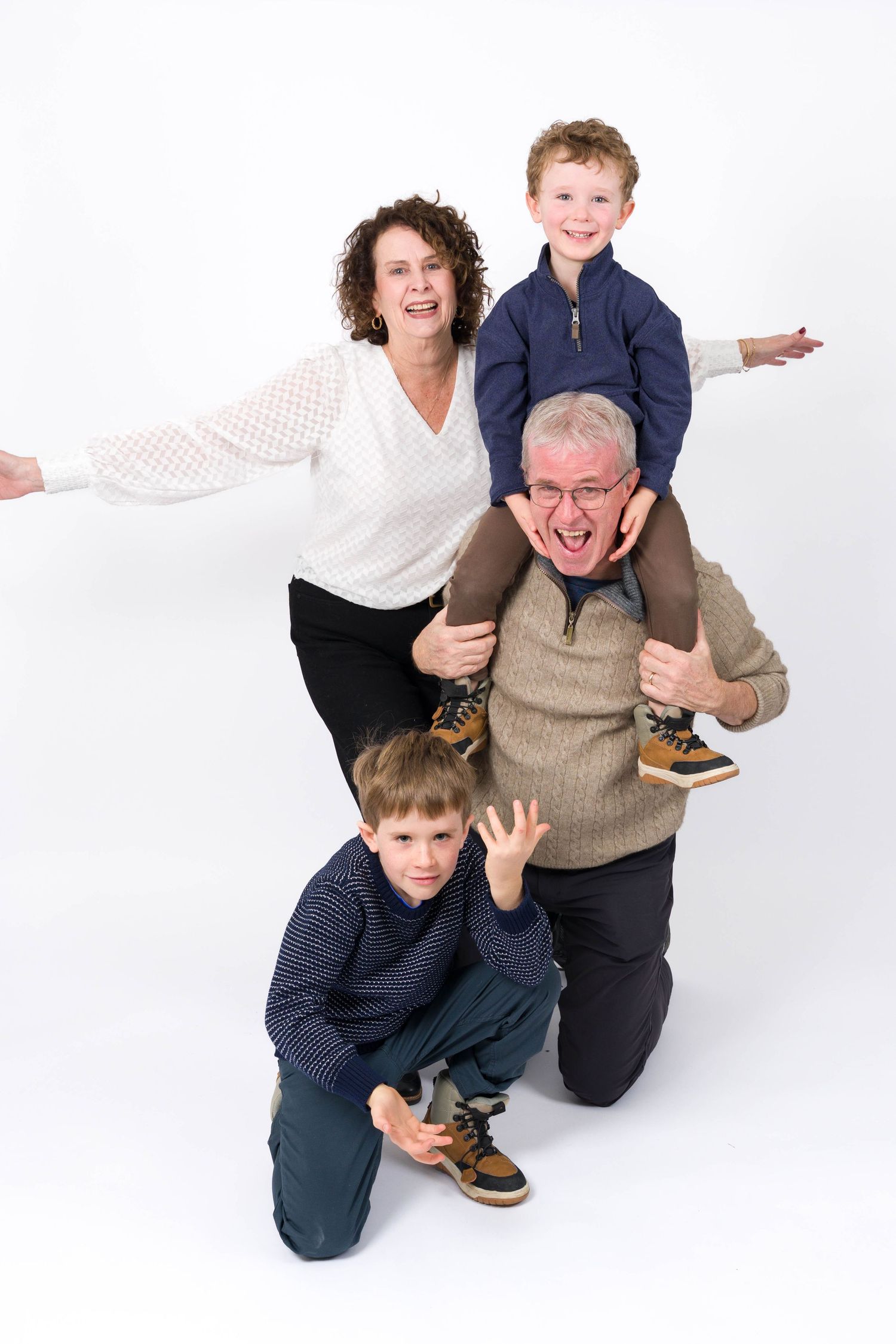 Playful family having fun and laughing together on white background in studio portrait sequence.