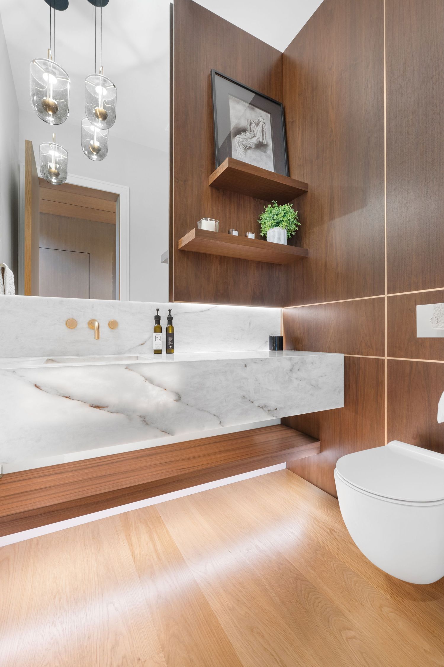 Minimalist bathroom design with floating marble vanity, wood accents, and pendant lighting.