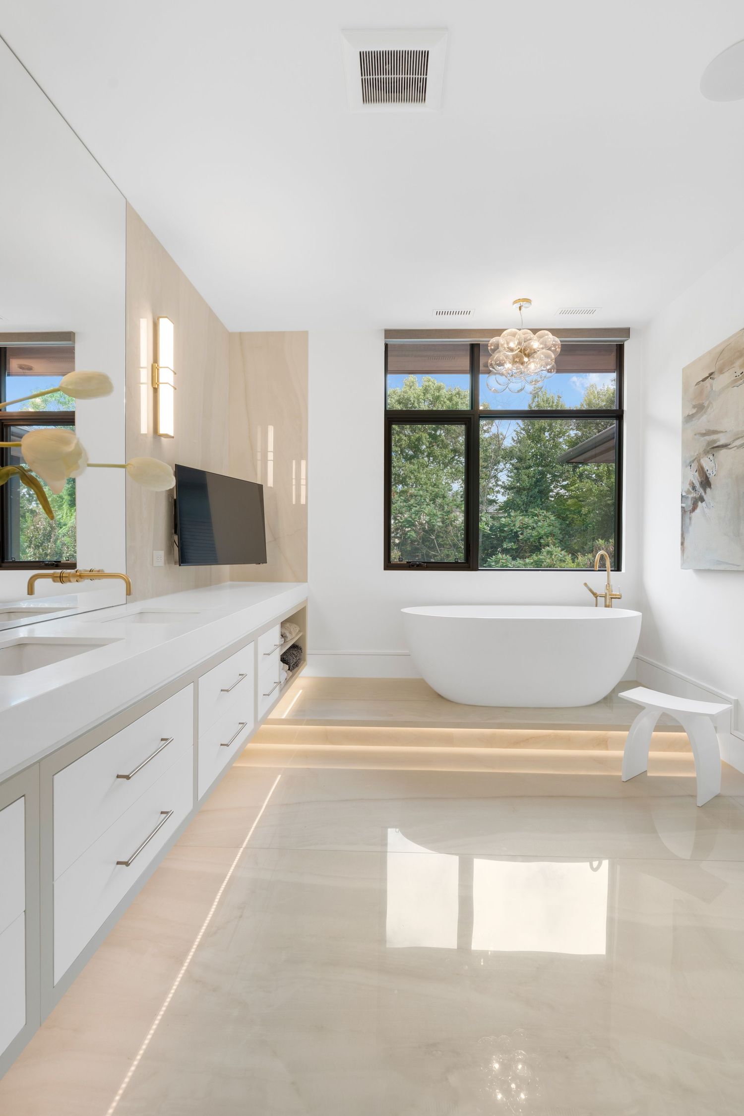 Spacious master bathroom featuring white cabinetry, modern fixtures, and abundant natural lighting.