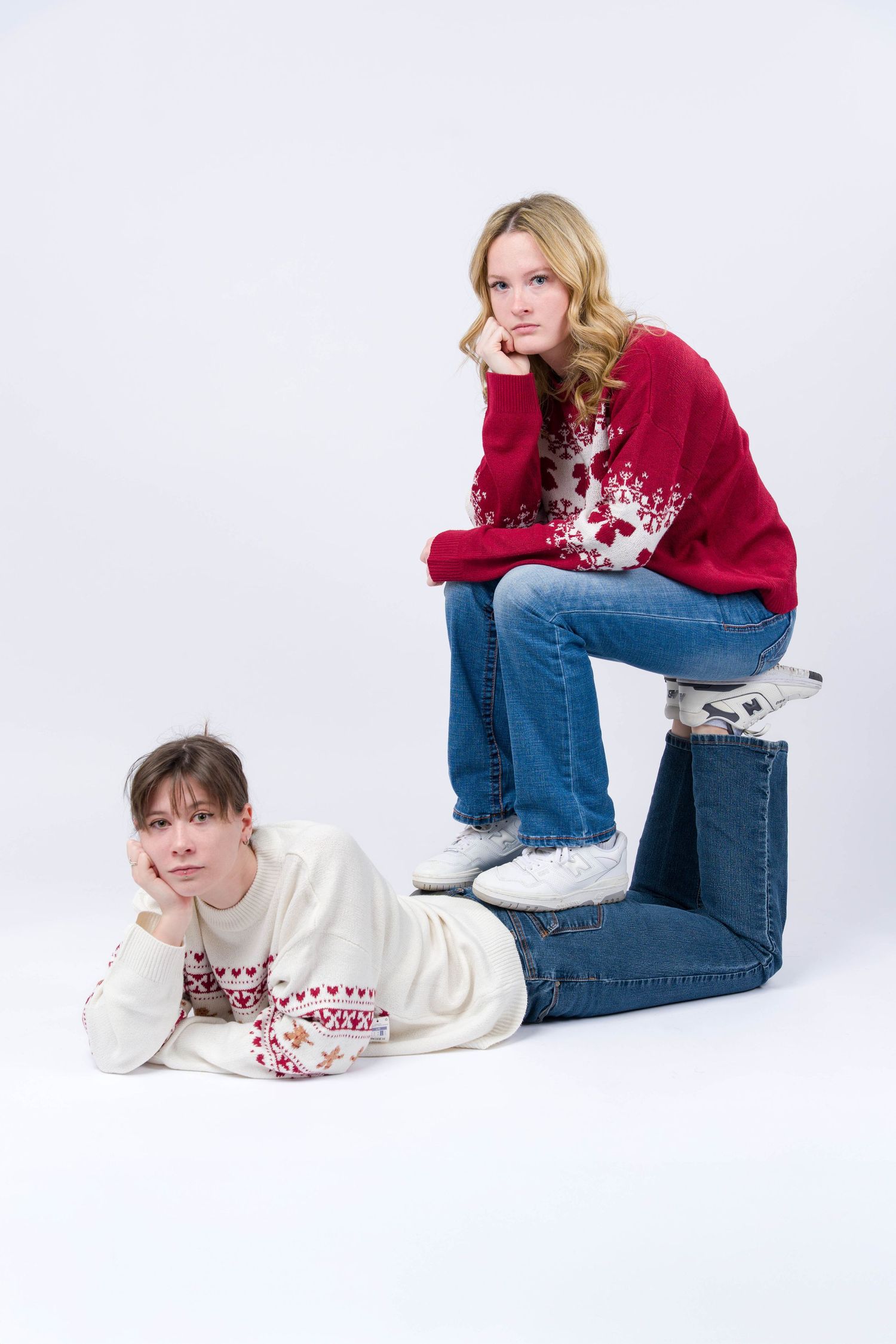 Two people in winter sweaters pose casually on a white backdrop in a photo series.