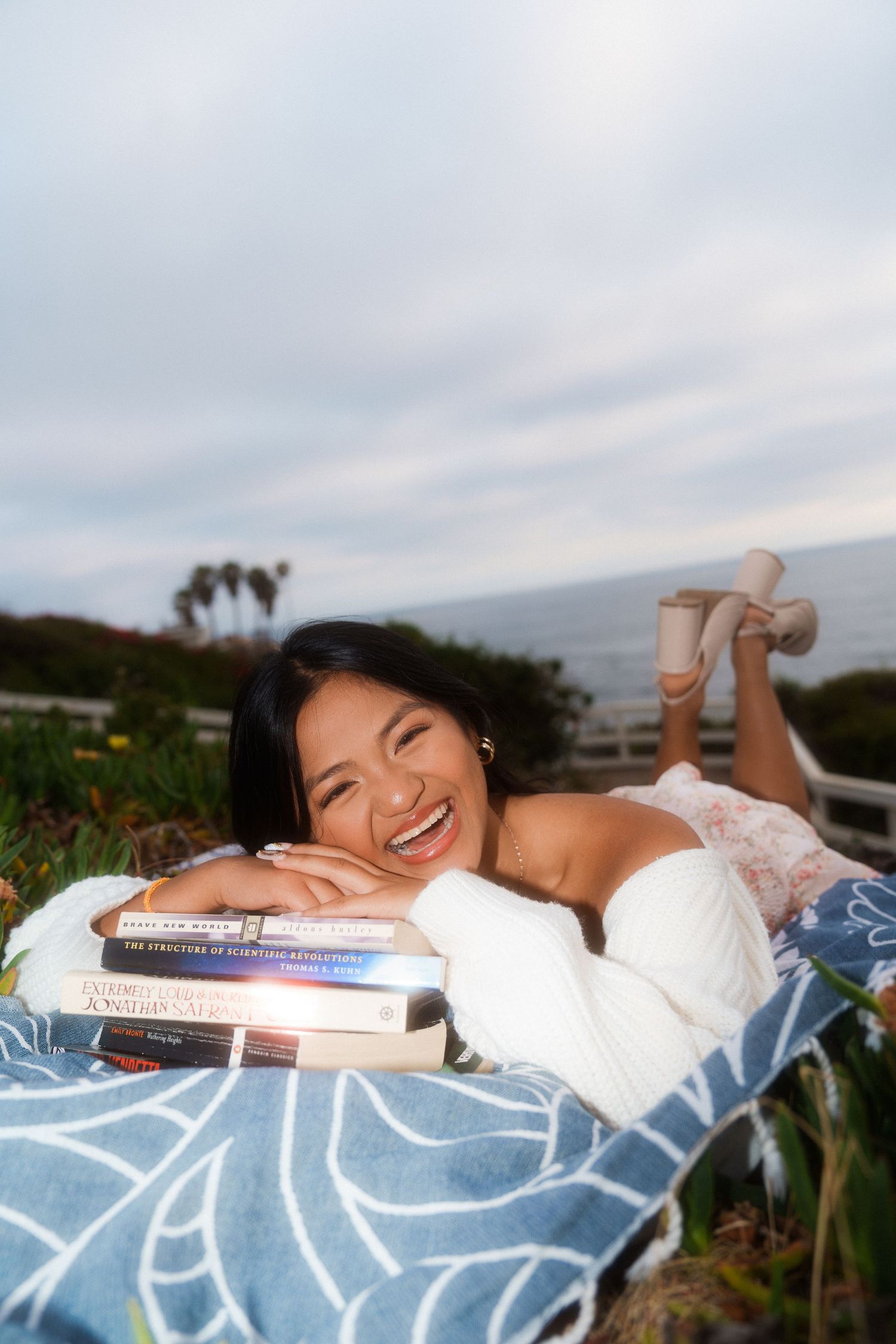 girl laying down on a blanket laying her chin on books for a graduation photo