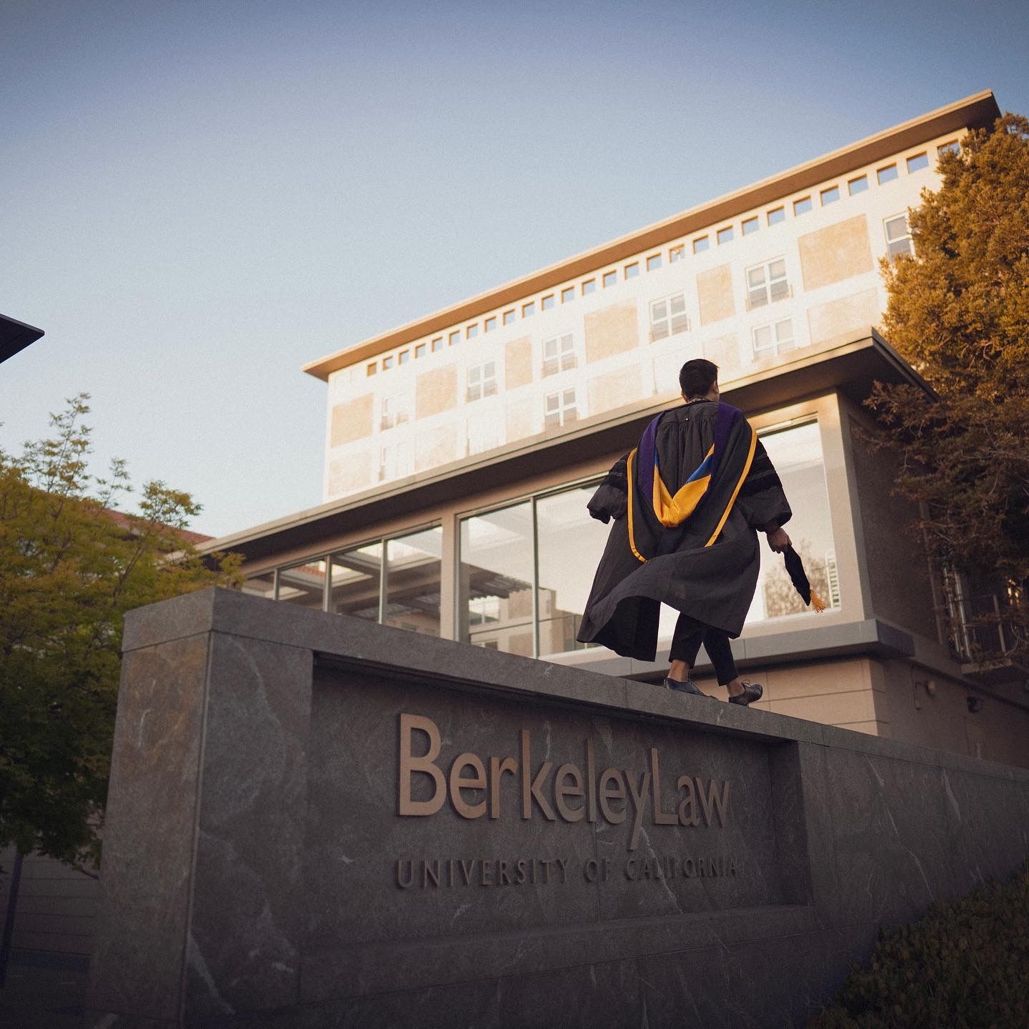 Man walking along a berkely law sign for a graduation photo