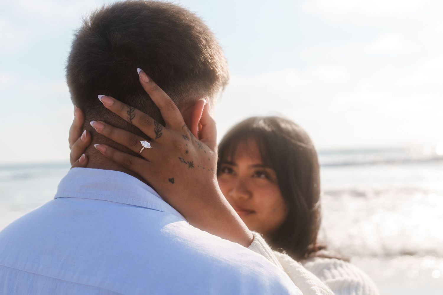 back of mans head with womans hands holding his neck with an engagement ring on her finger for a engagement photoshoot