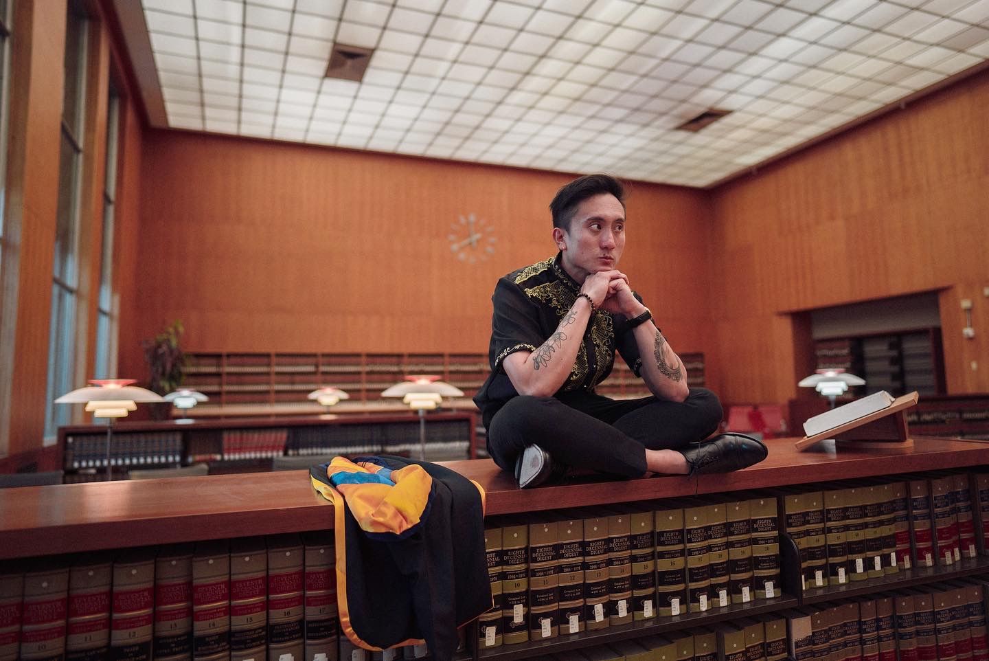 man sitting on a bookshelf for a graduation photo