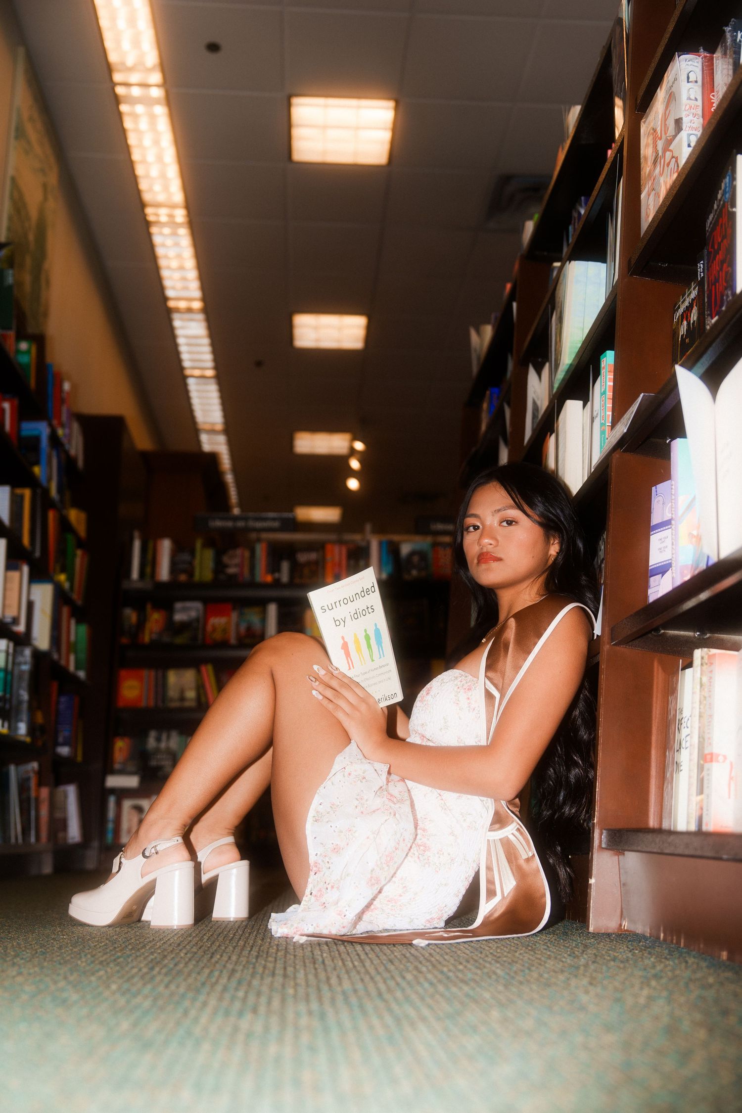girl sitting down in hallway of library reading a book called 