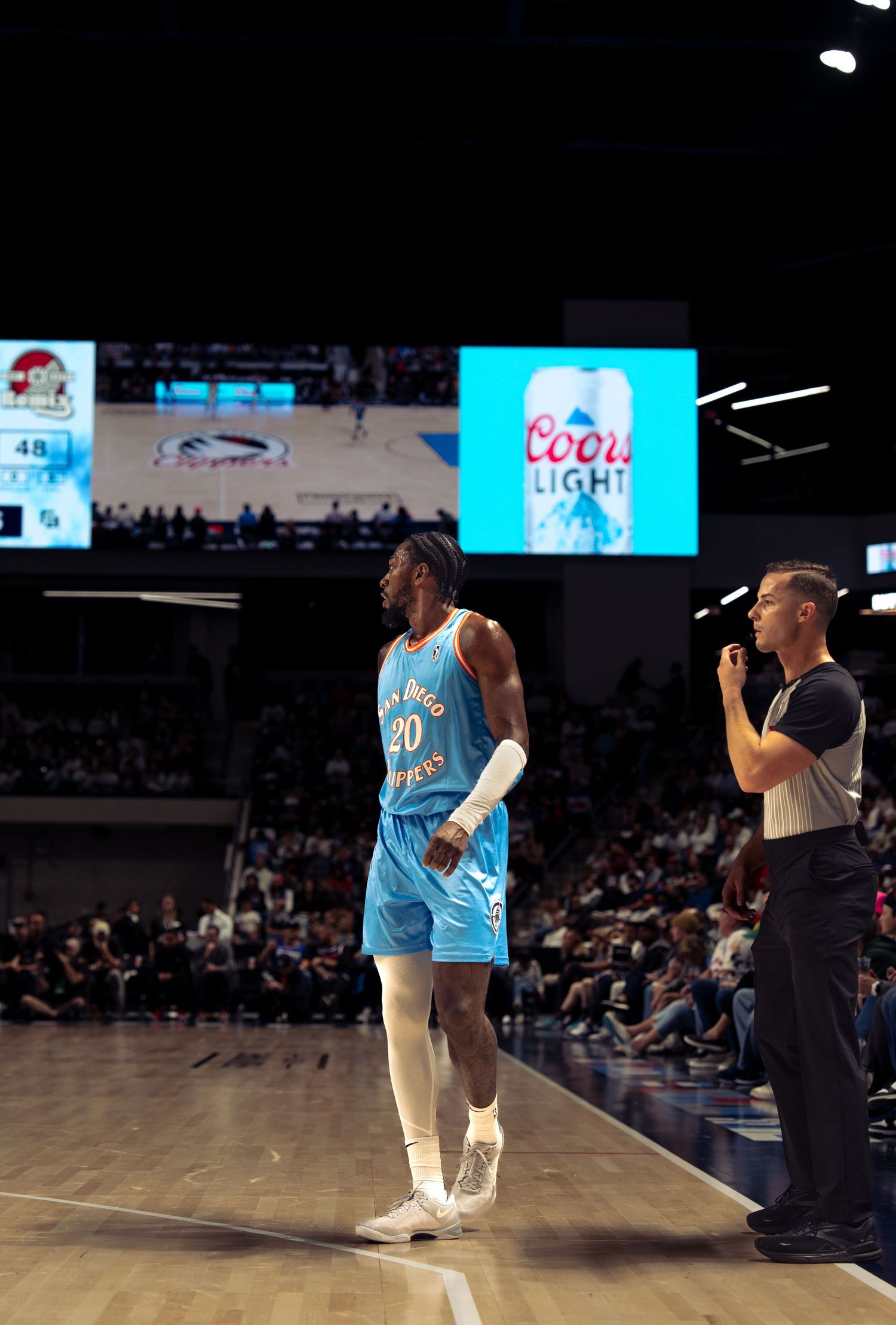 Basketball performers entertain the crowd during a game break at an indoor arena with blue lighting effects.