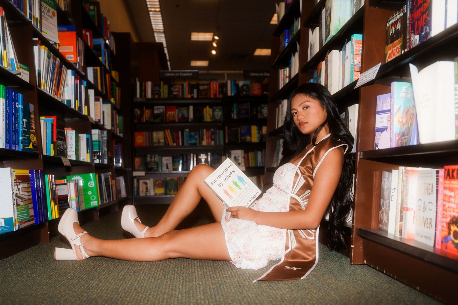 girl sitting down in hallway of library reading a book called 