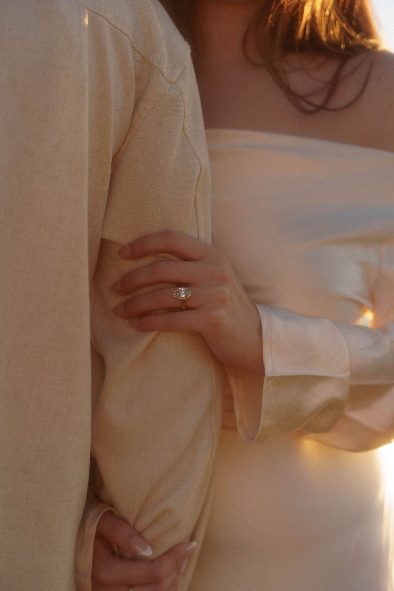 A series of soft, romantic images showing hands gently touching white fabric in warm lighting.