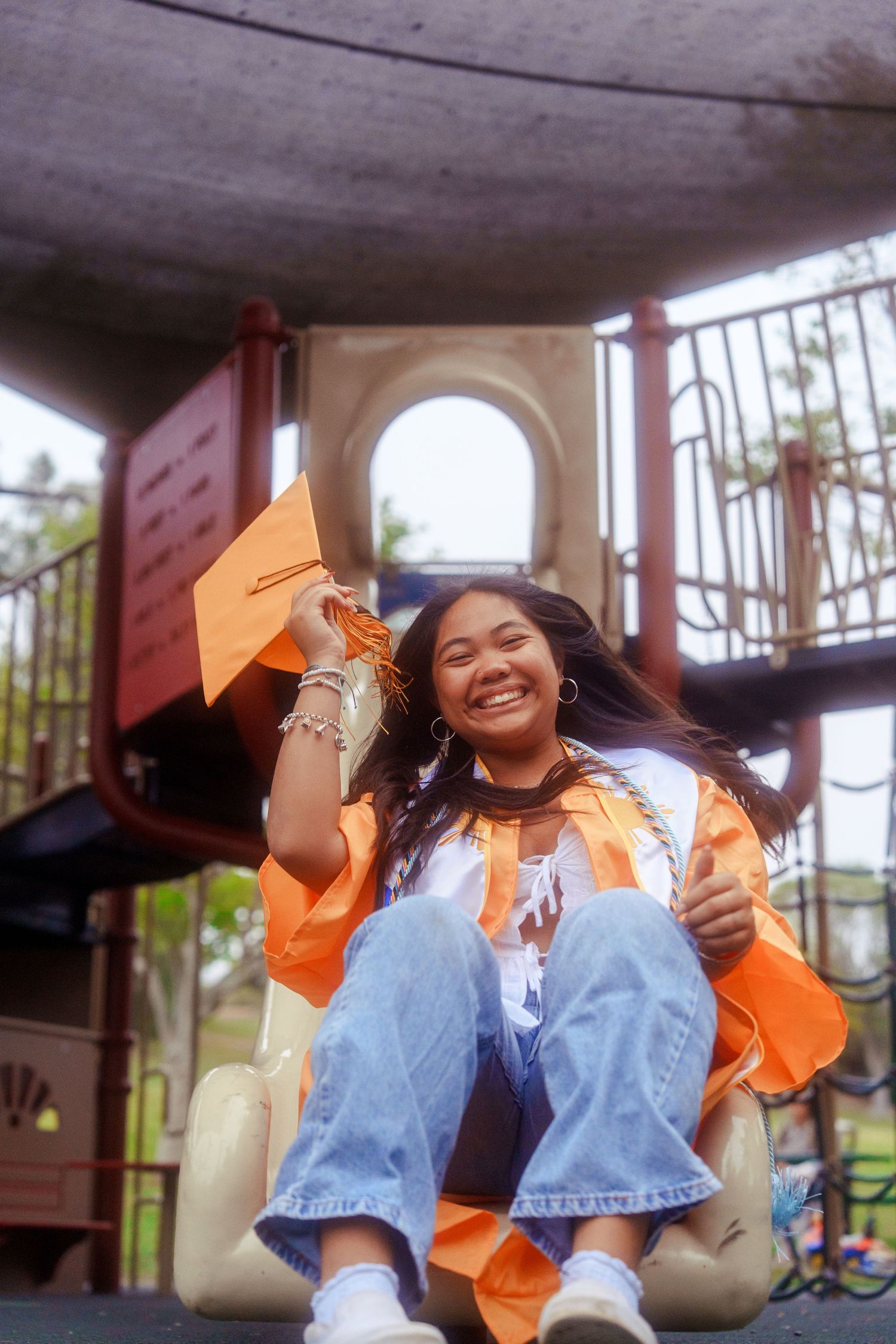 girl sliding down a slide in an action shot for a graduation photo
