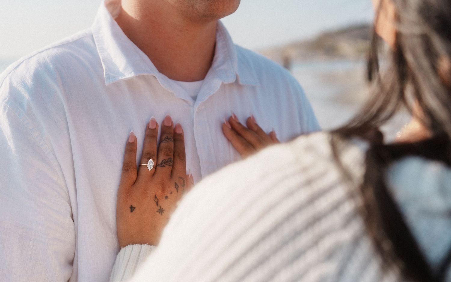 photo of girls hand on mans chest with the engagement ring being very prominent in the photo