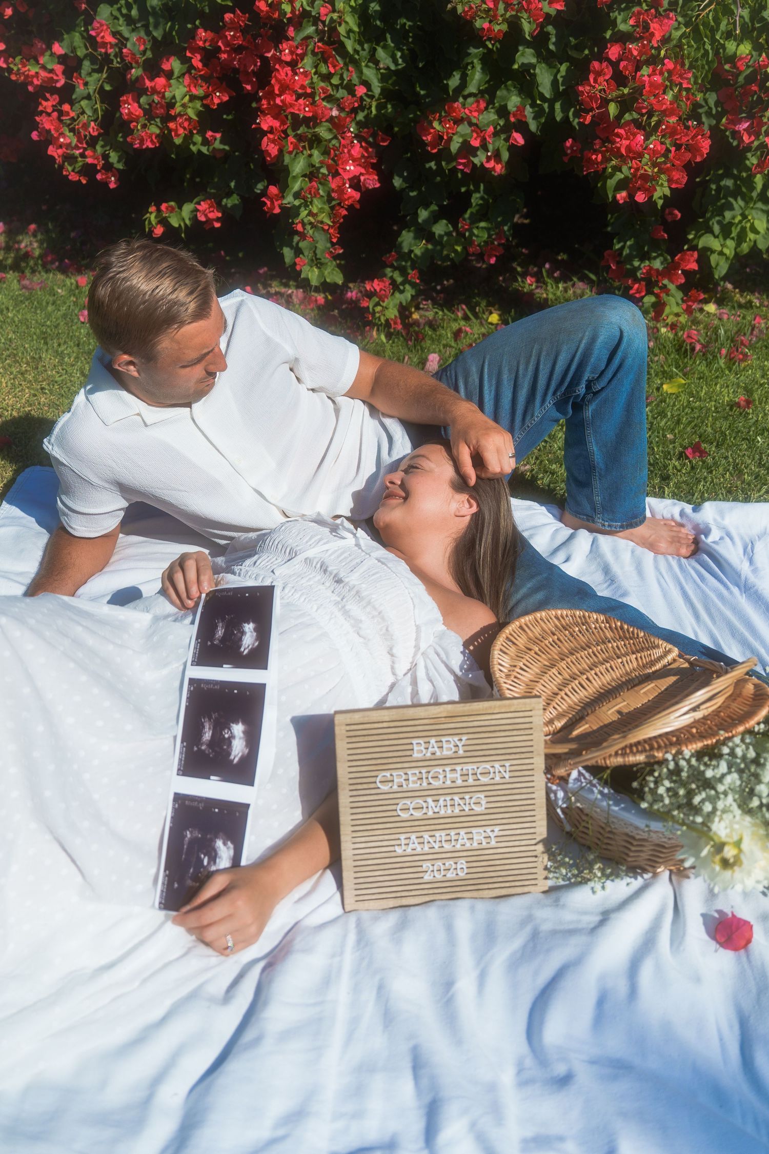 woman laying on mans lap while he sits in a dreamy baby announcement photoshoot
