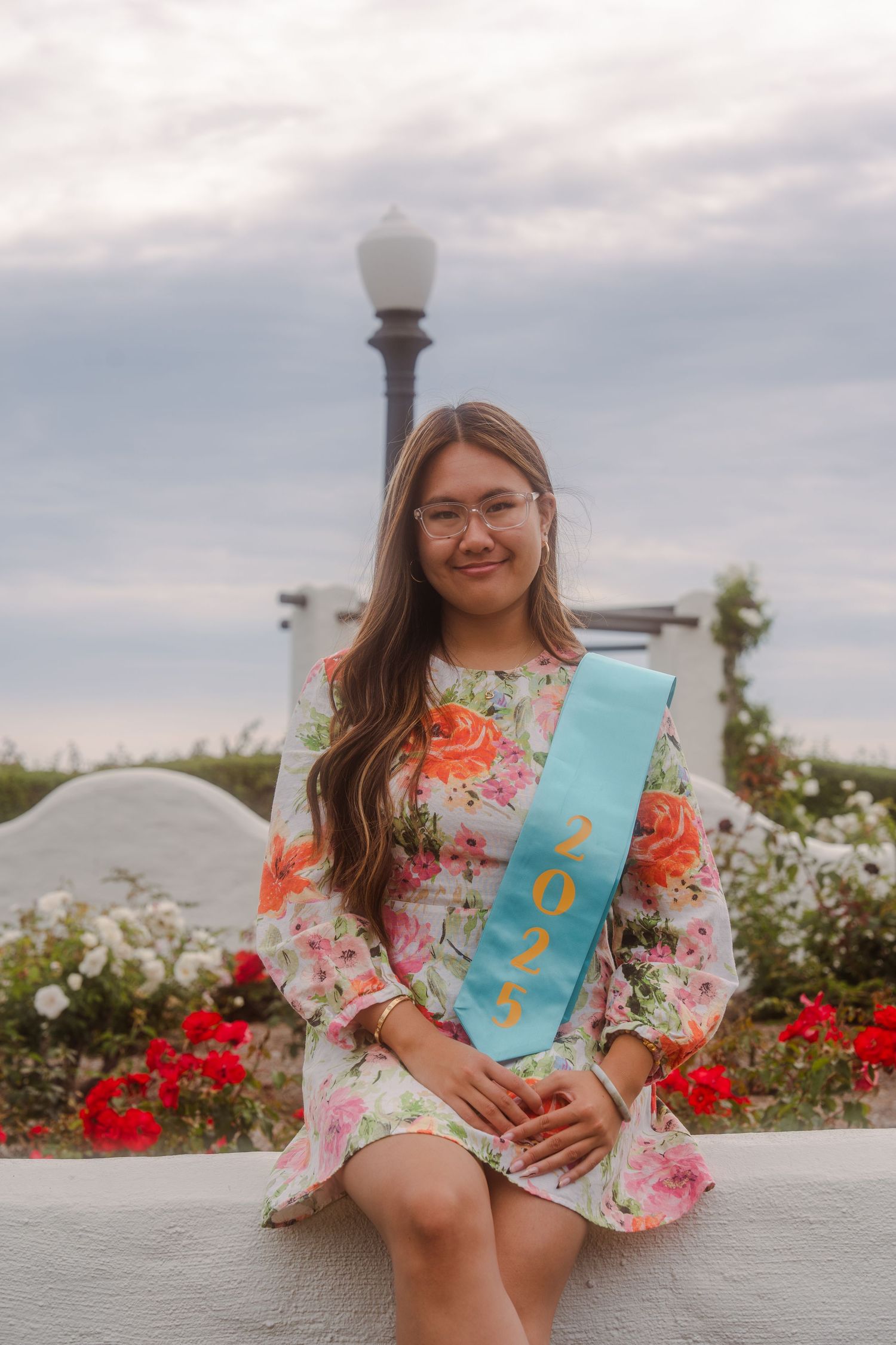 graduation photo of a girl sitting down posing