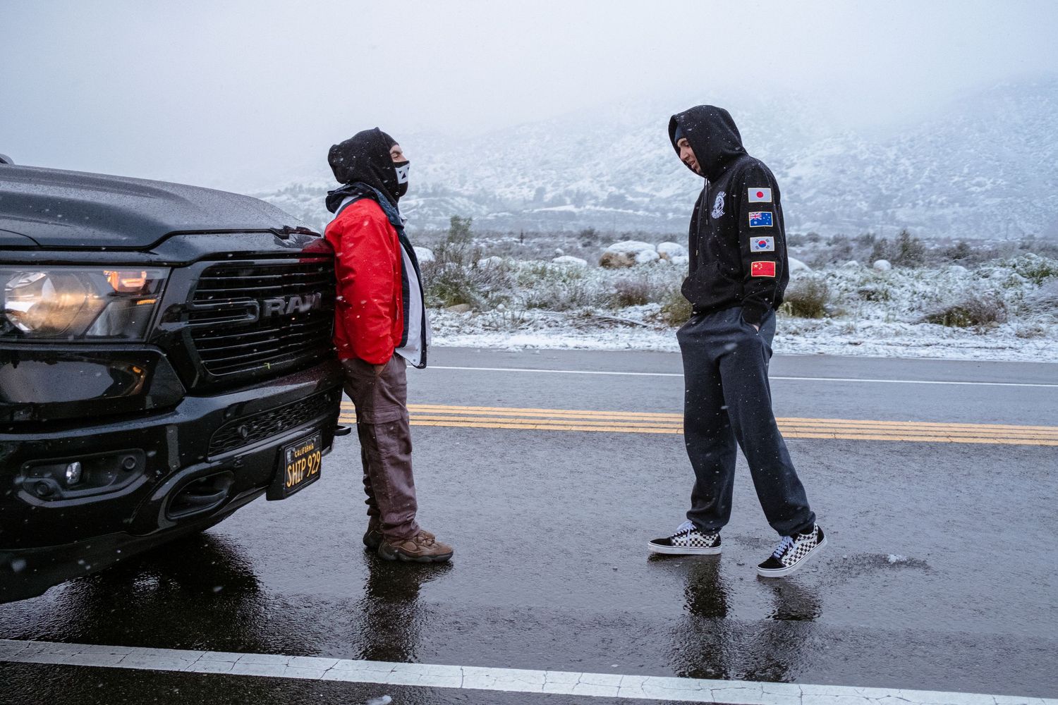 2 men standing, conversing in the snow