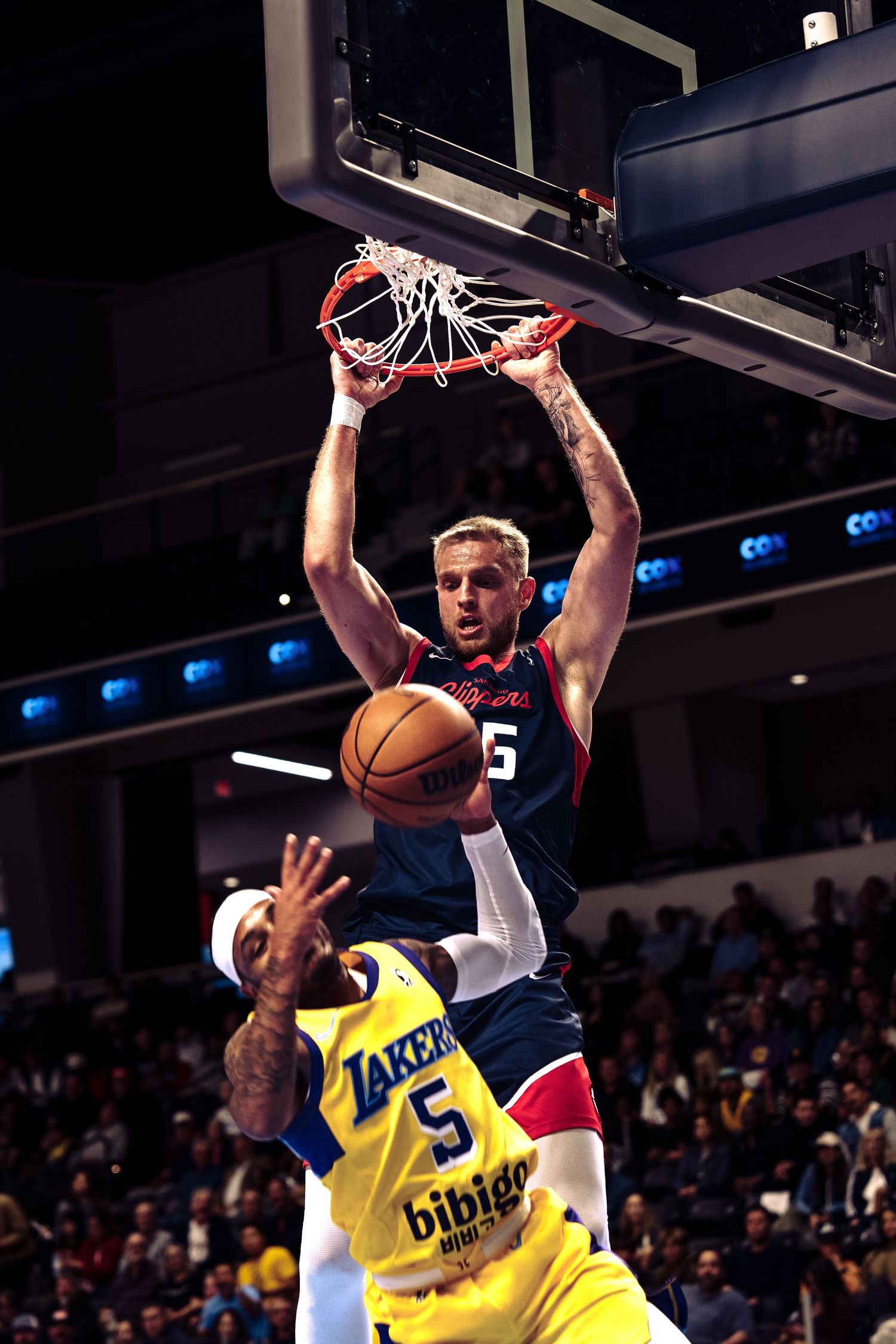 Basketball player in for the San Diego Clippers, drives to the basket and dunks on a South Bay Lakers Player.