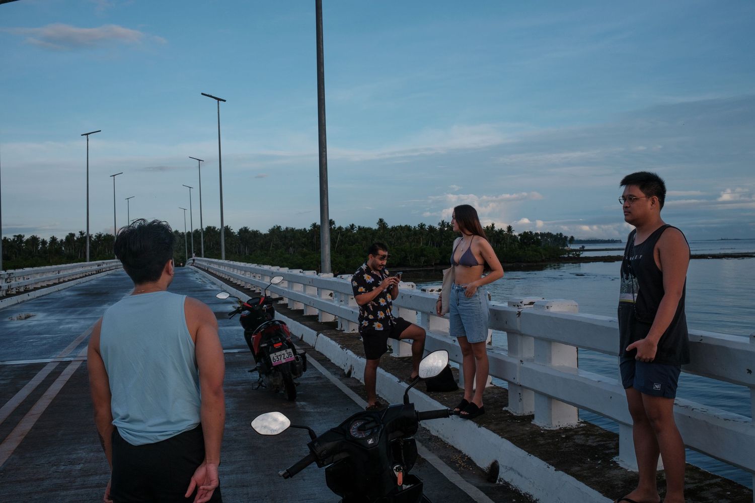 Group of people on vacation next to motorcycles on a bridge in siargao