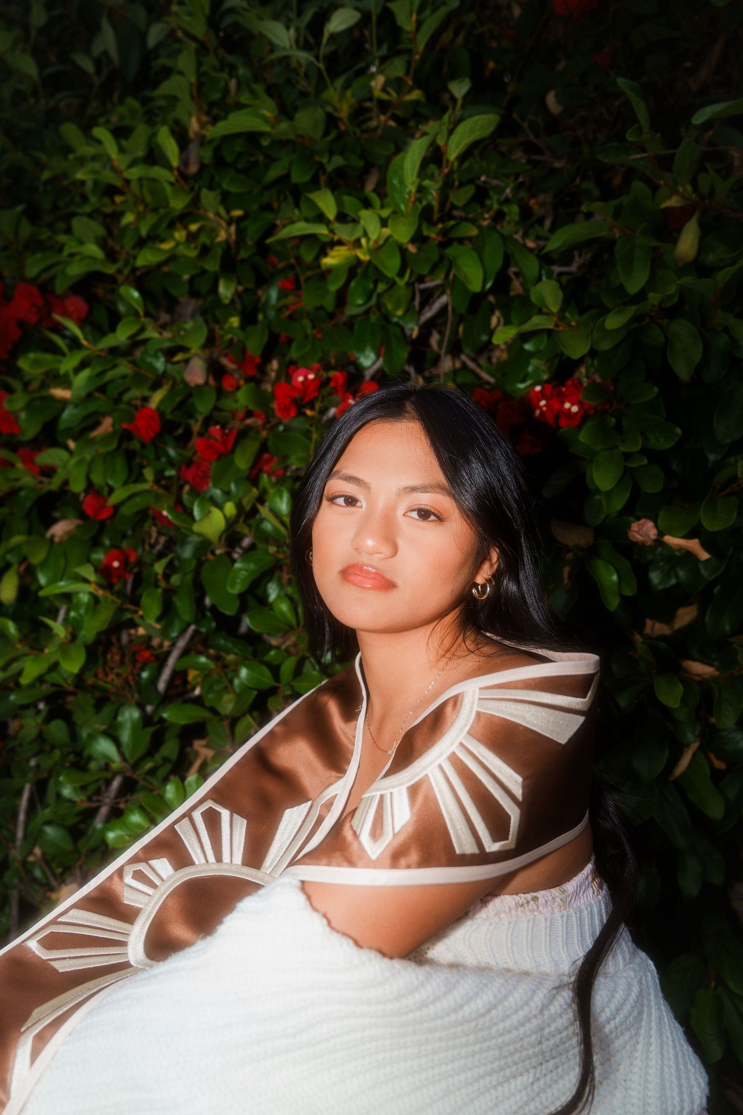 girl squatting next to a bush looking at the camrea for a graduation photo